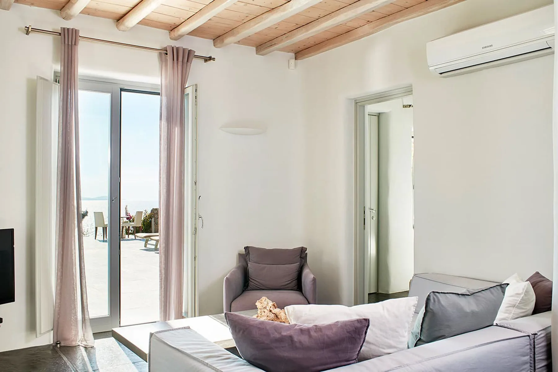 A bright bedroom with a bed and an open doorway to a balcony.