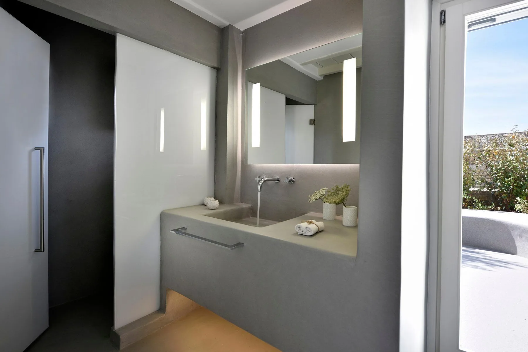 A modern bathroom with a wide sink counter and a large mirror.