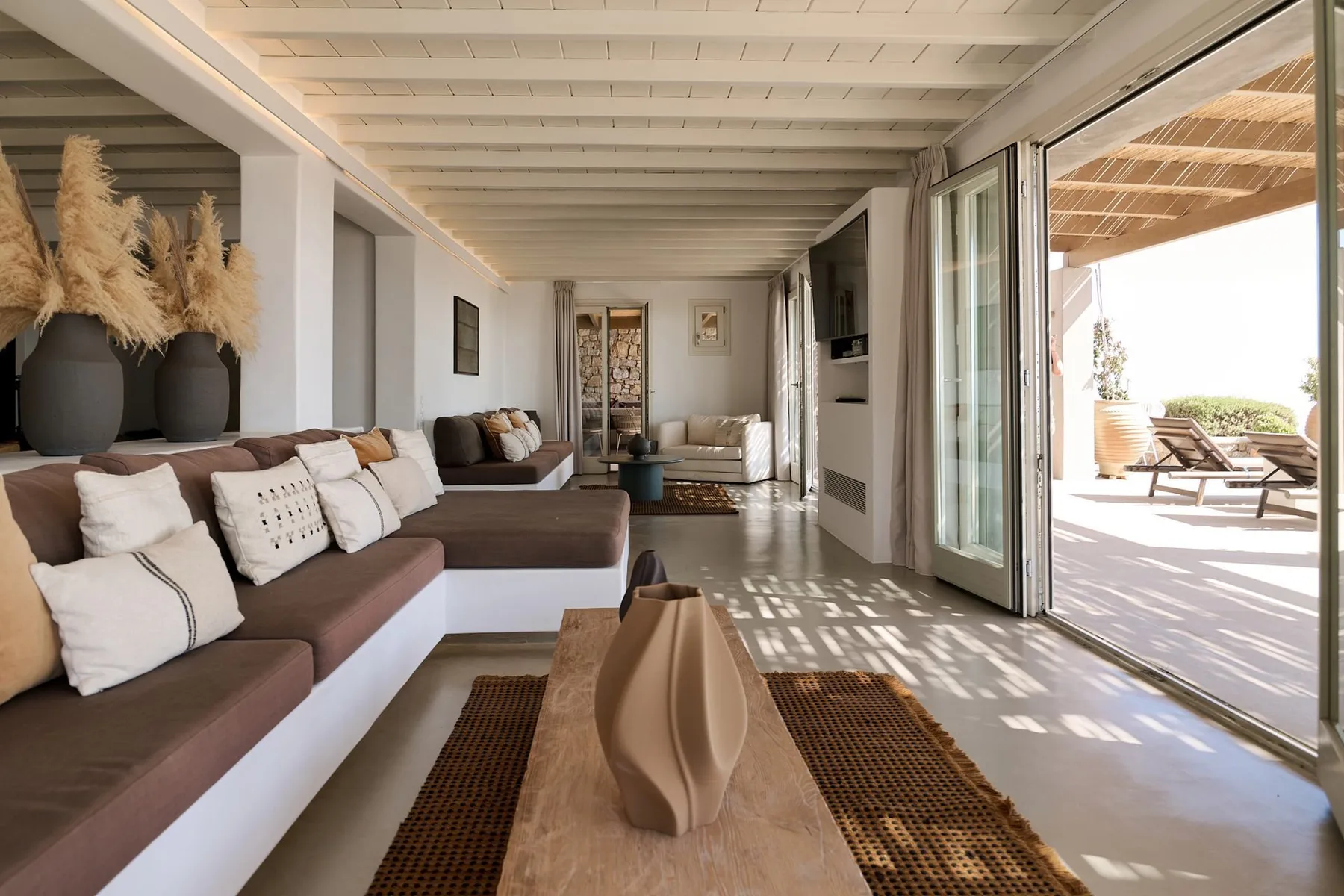 A bright living room with built-in seating and open glass doors to a patio.