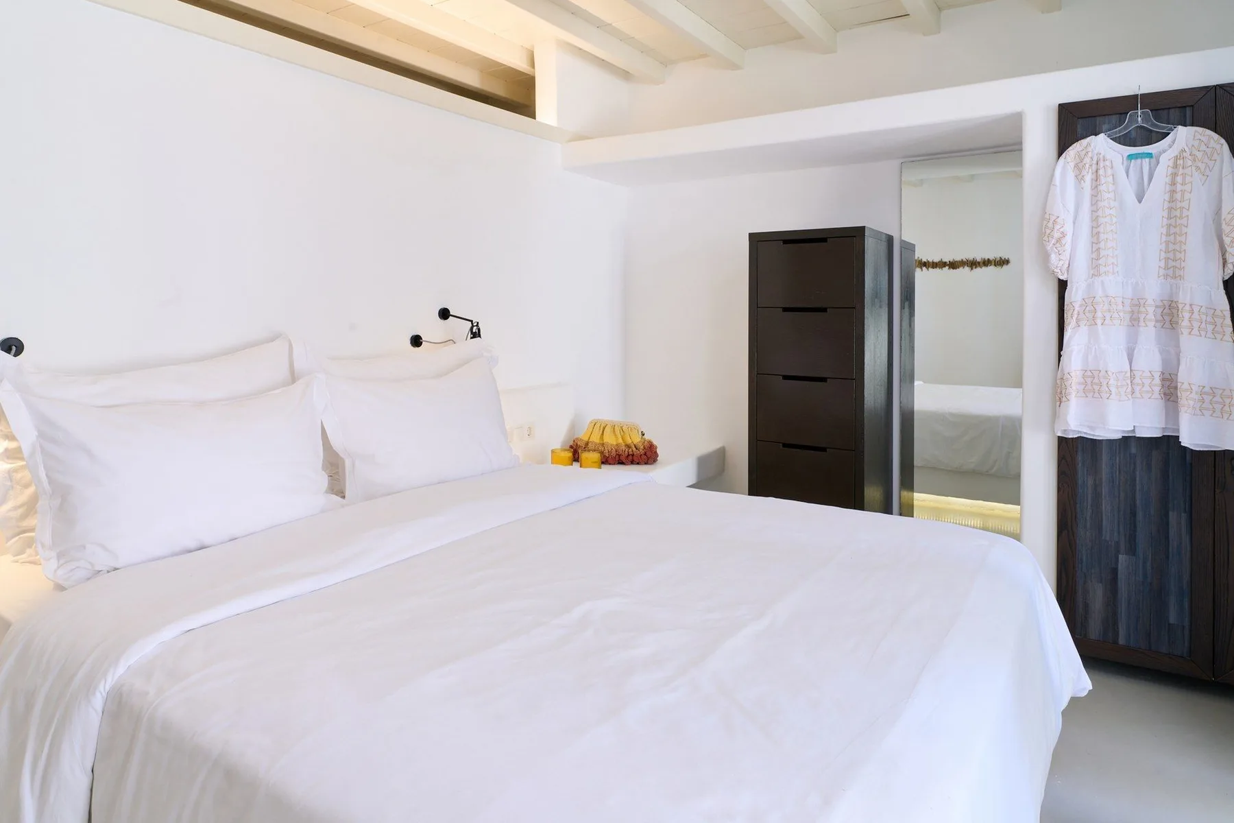 A bright bedroom with a neatly made bed and a wardrobe beside it.