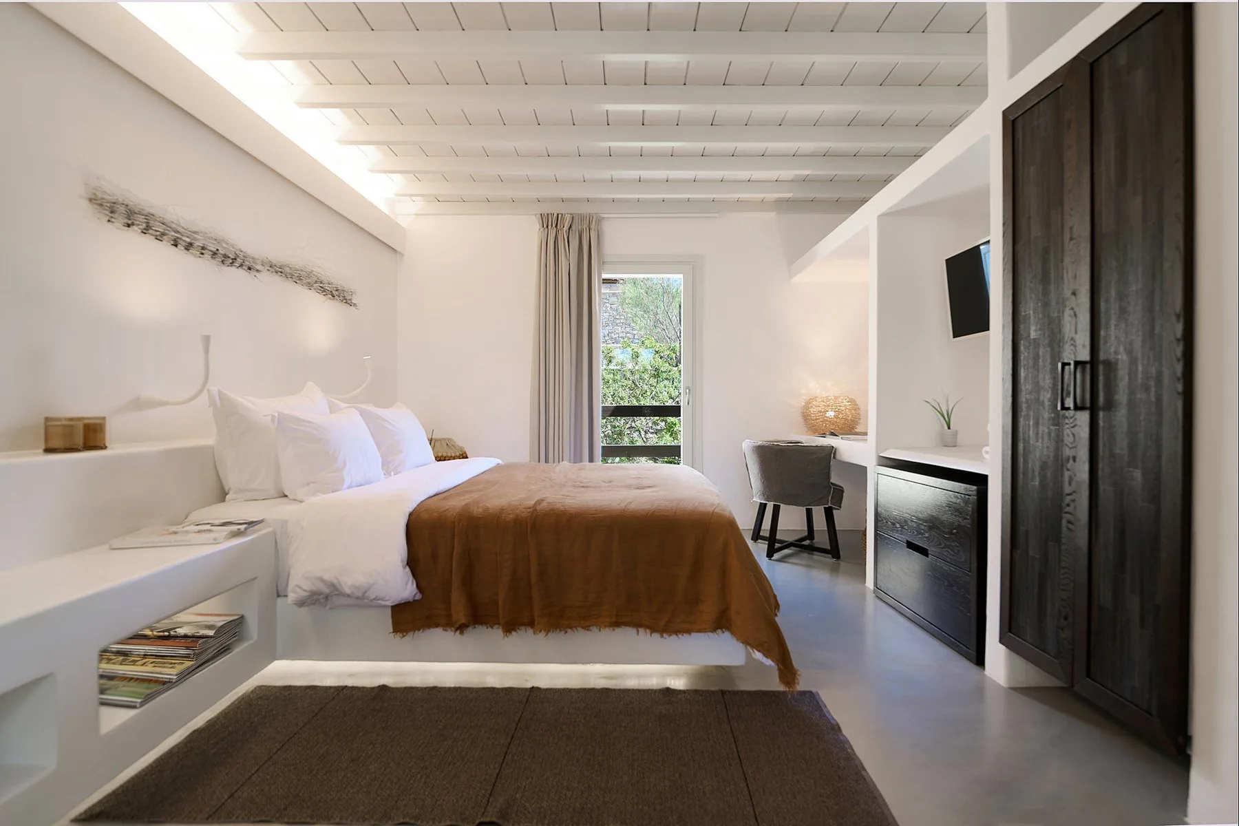 A bright bedroom with a bed, white bedding, and a brown cover.