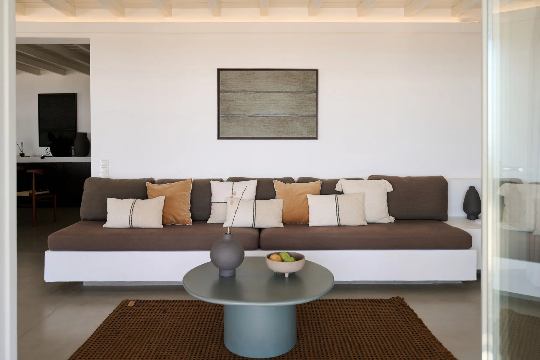 A living room with a long sofa, a round coffee table, and a woven rug.
