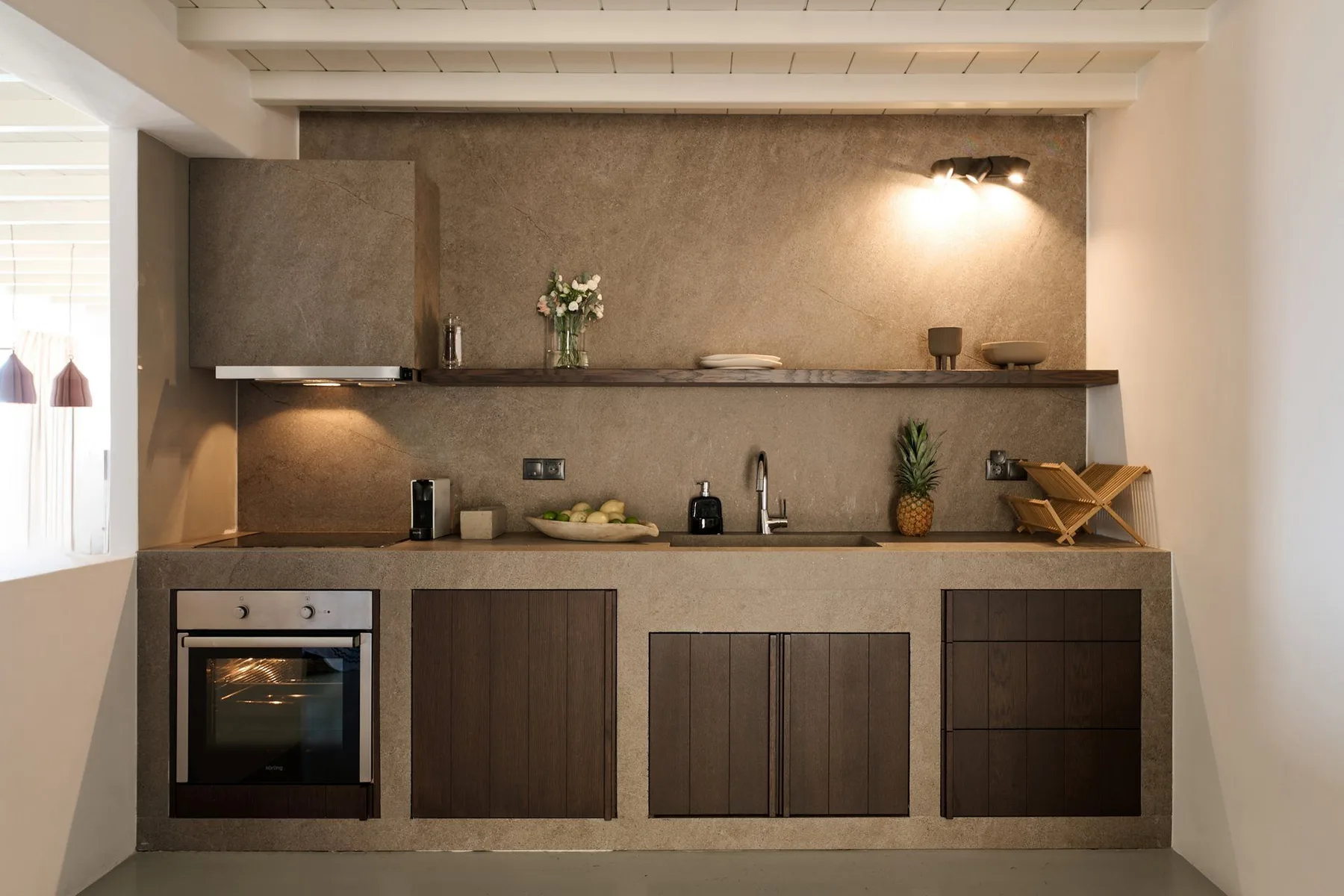 A compact kitchen with dark cabinetry, a countertop, and an oven.