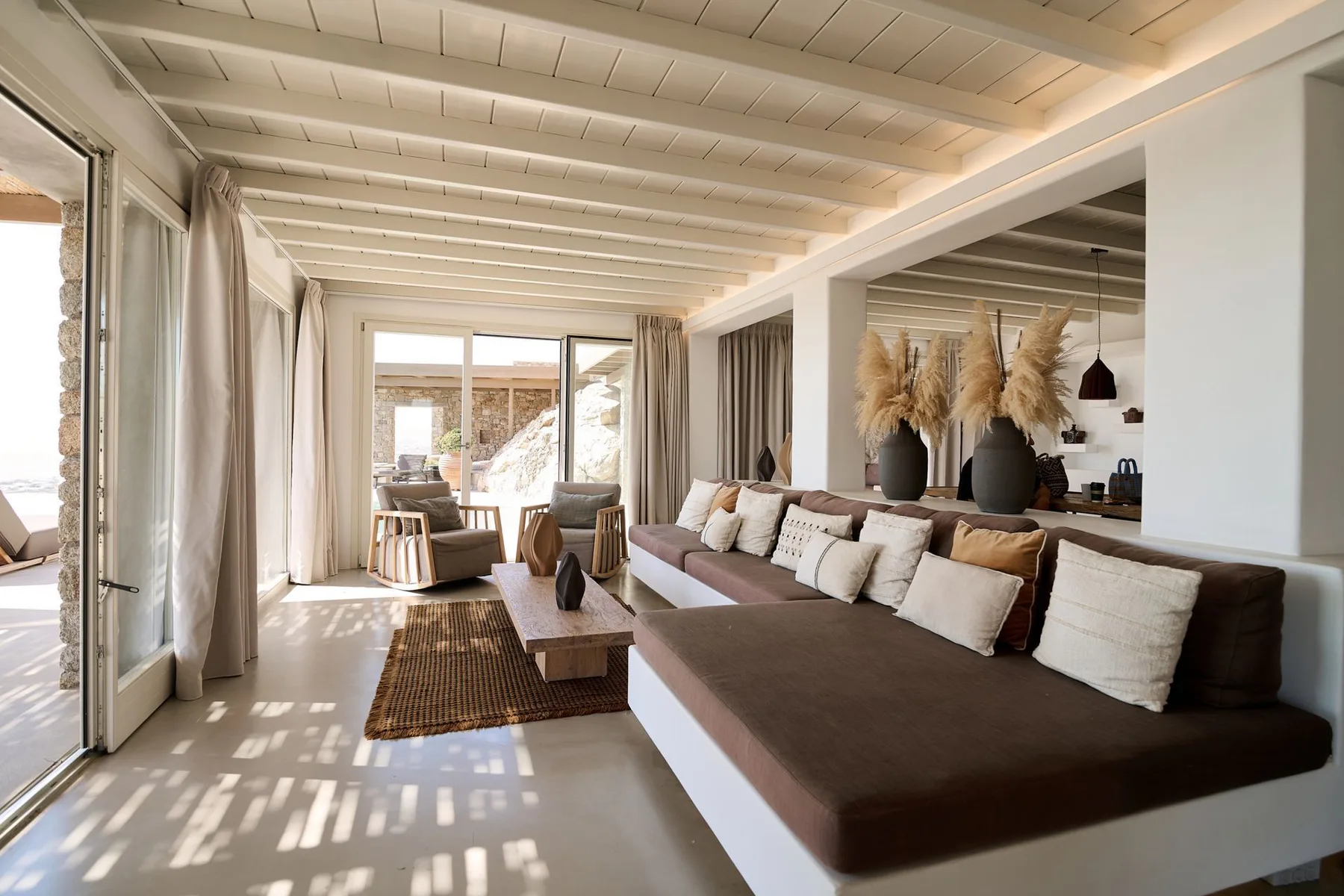 A bright living room with a long sofa, coffee table, and glass doors.