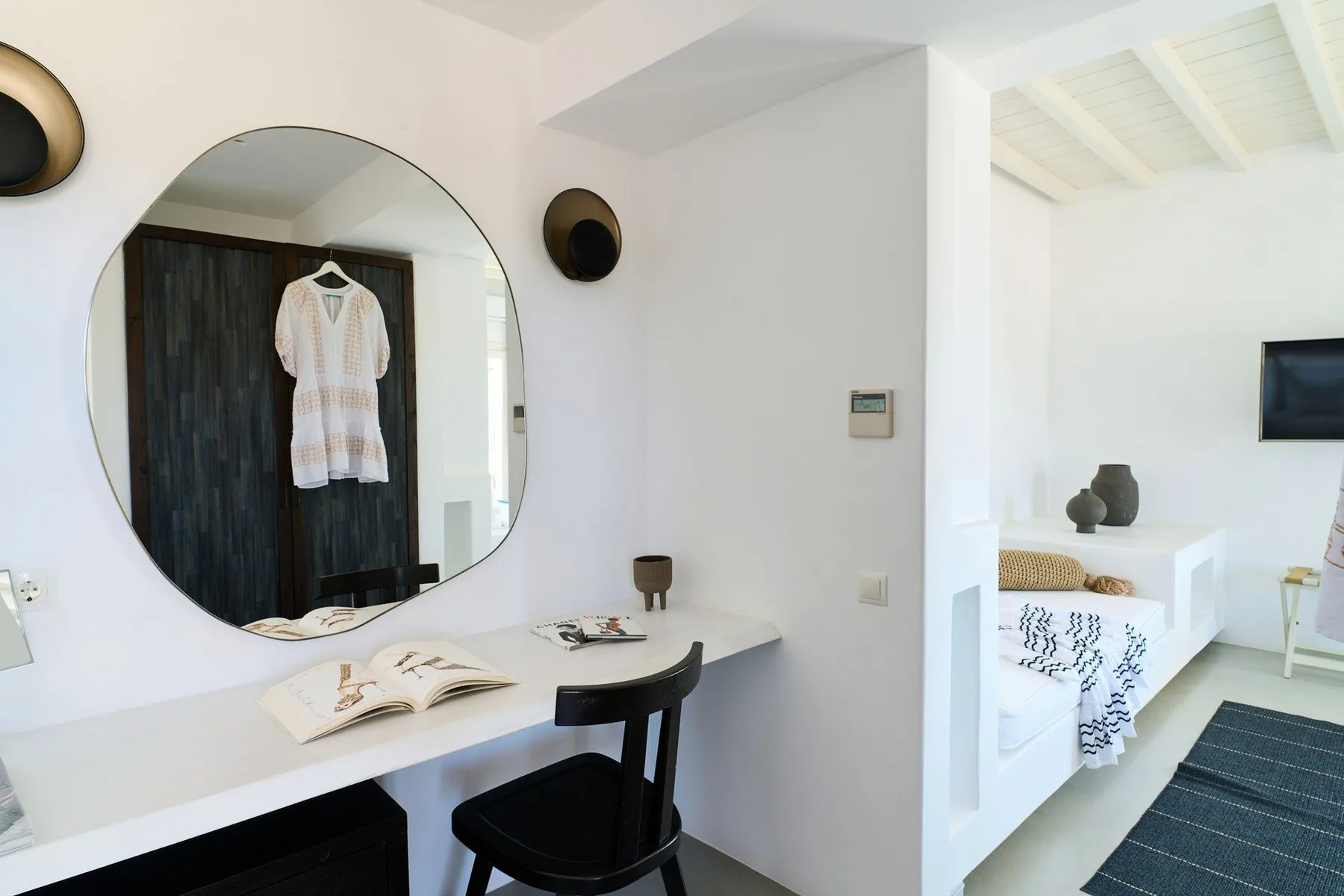 A bright room with a desk and mirror beside a sitting area.