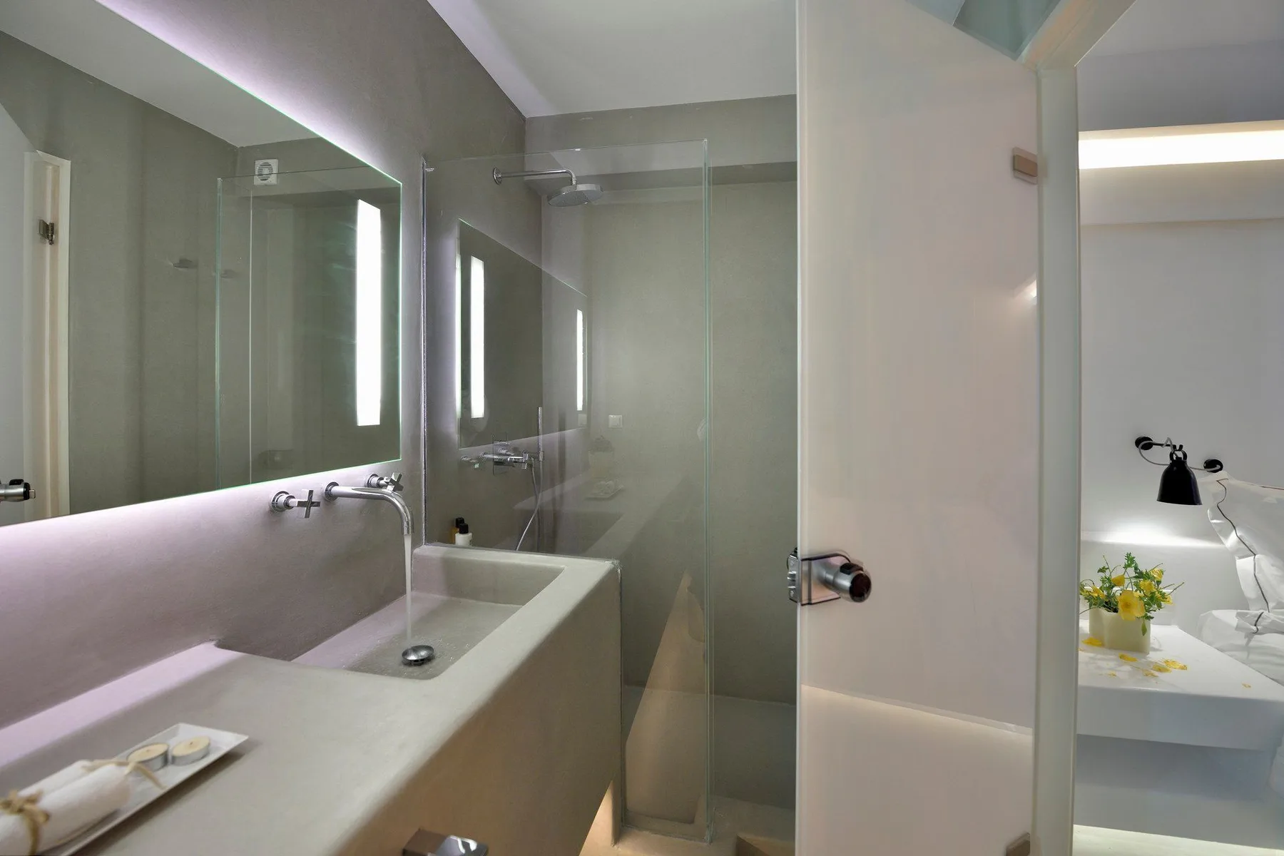 A modern bathroom with a wide sink counter and glass shower.