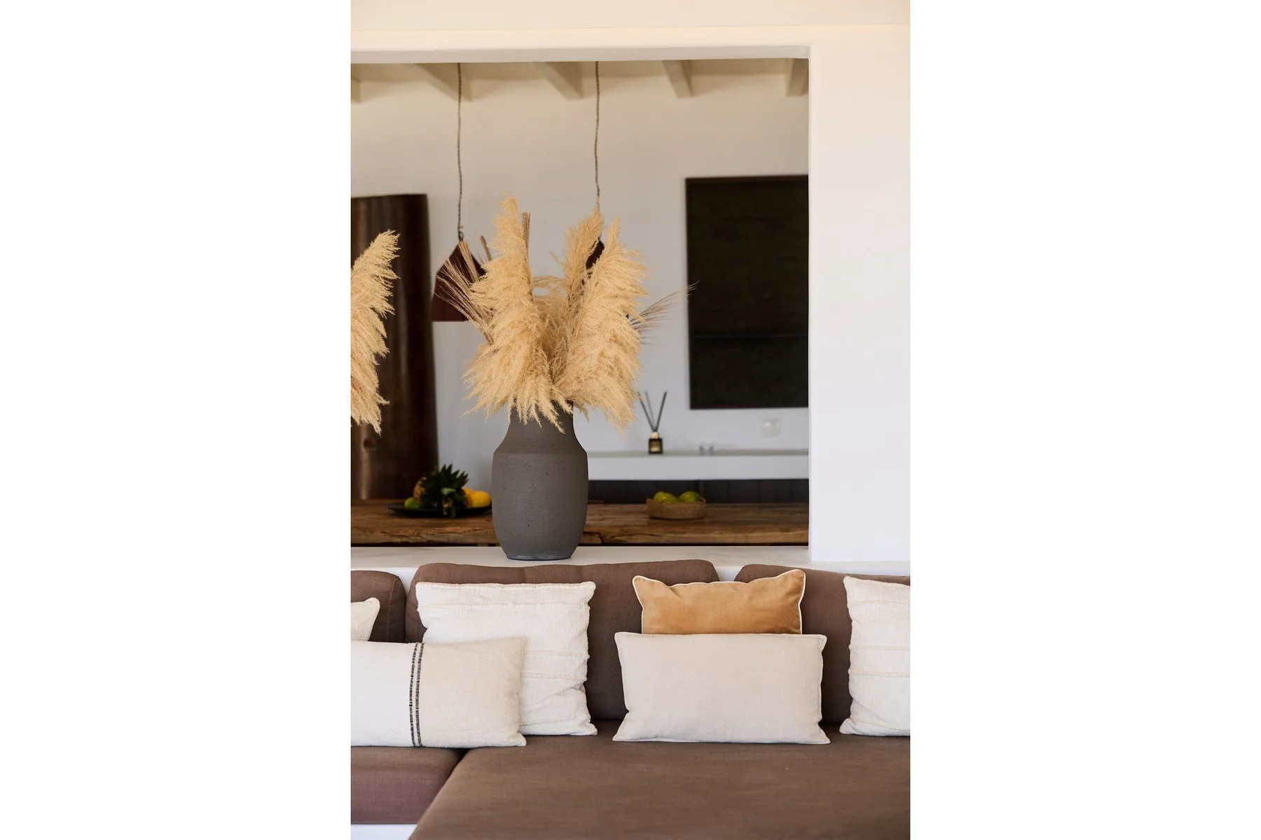 A living room seating area with neutral cushions and a vase of dried grasses.