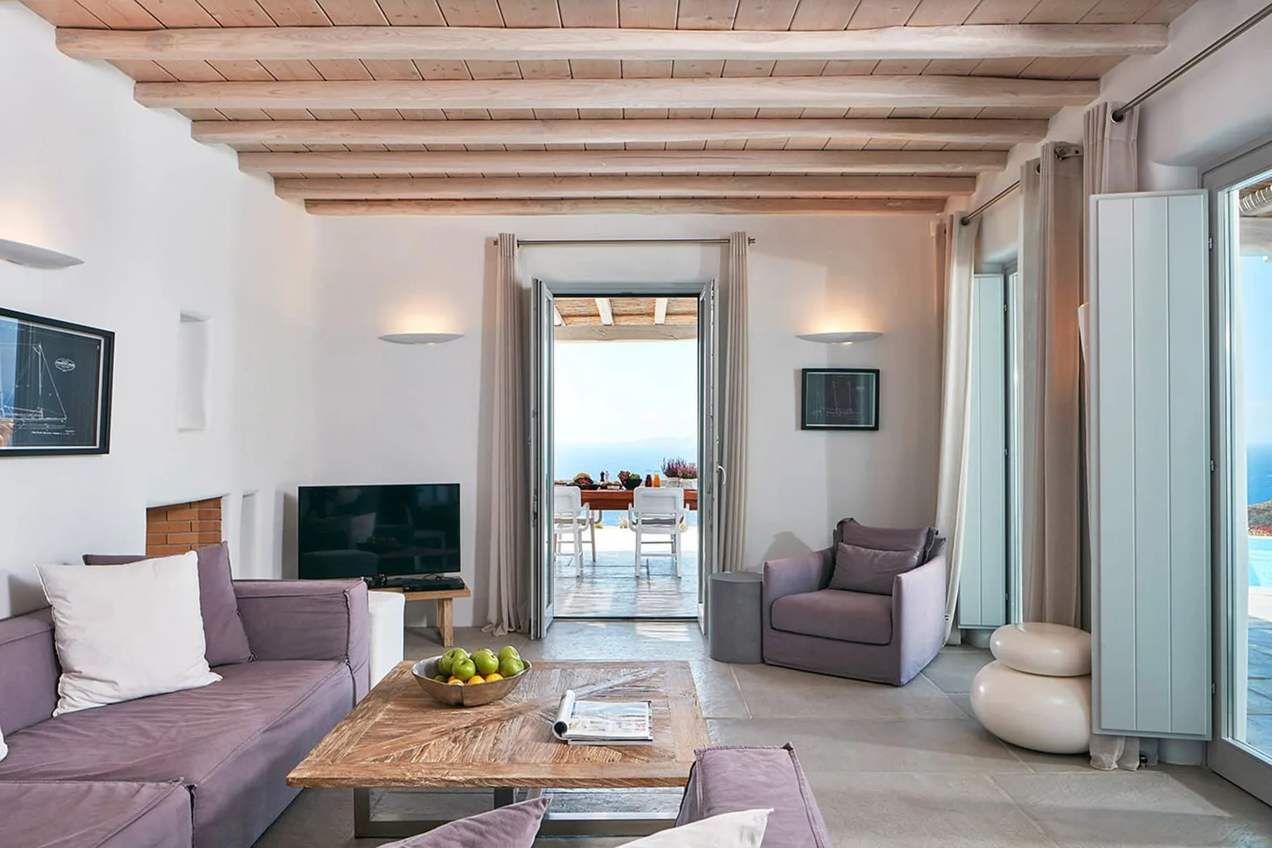 A bright living room with seating, a television, and an open doorway to a dining area.