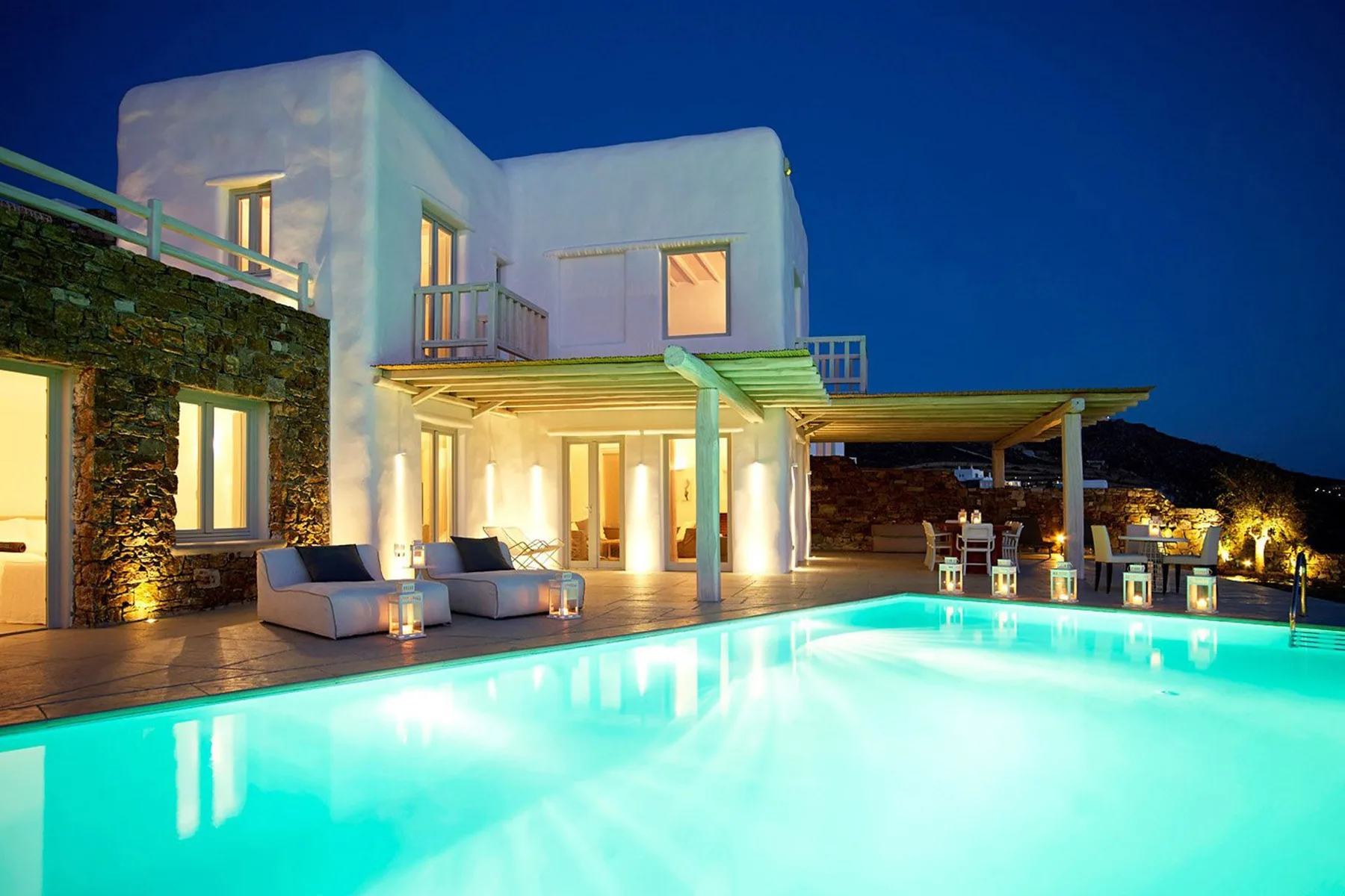 A modern house and outdoor swimming pool glow under the evening sky.