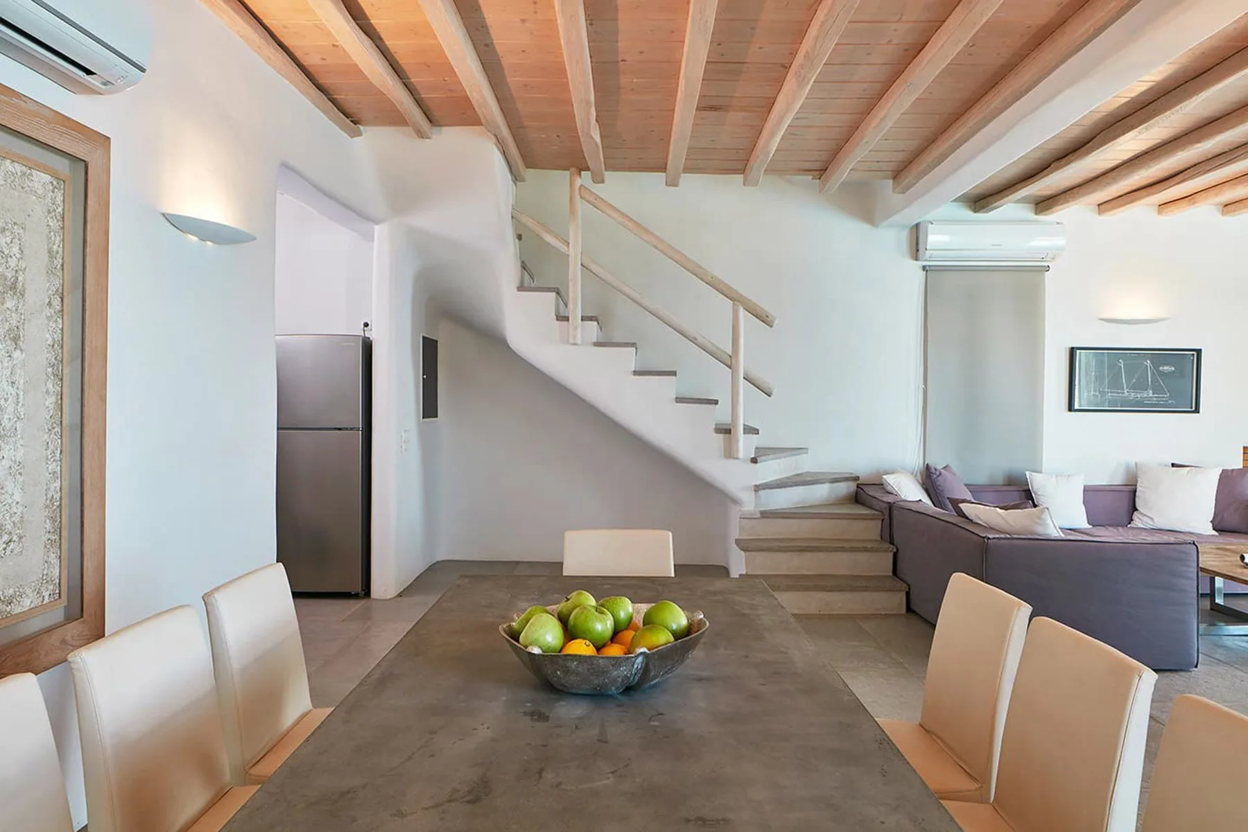 A dining area with a table and chairs beside a staircase and living area.