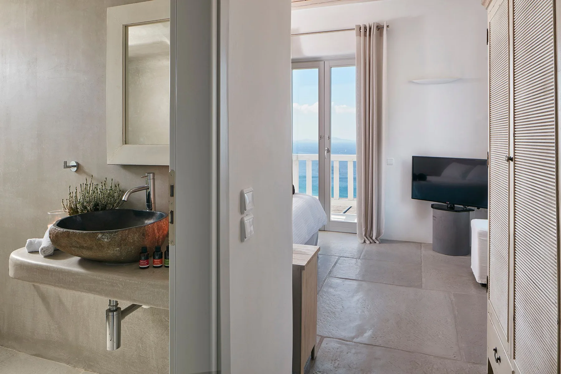 A bedroom and bathroom are visible, with a television and balcony doors.