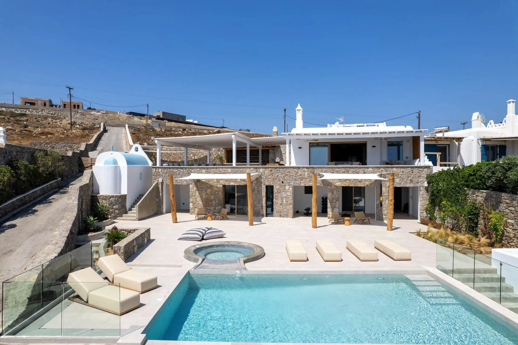 A modern villa patio features a swimming pool, a small spa, and outdoor seating.
