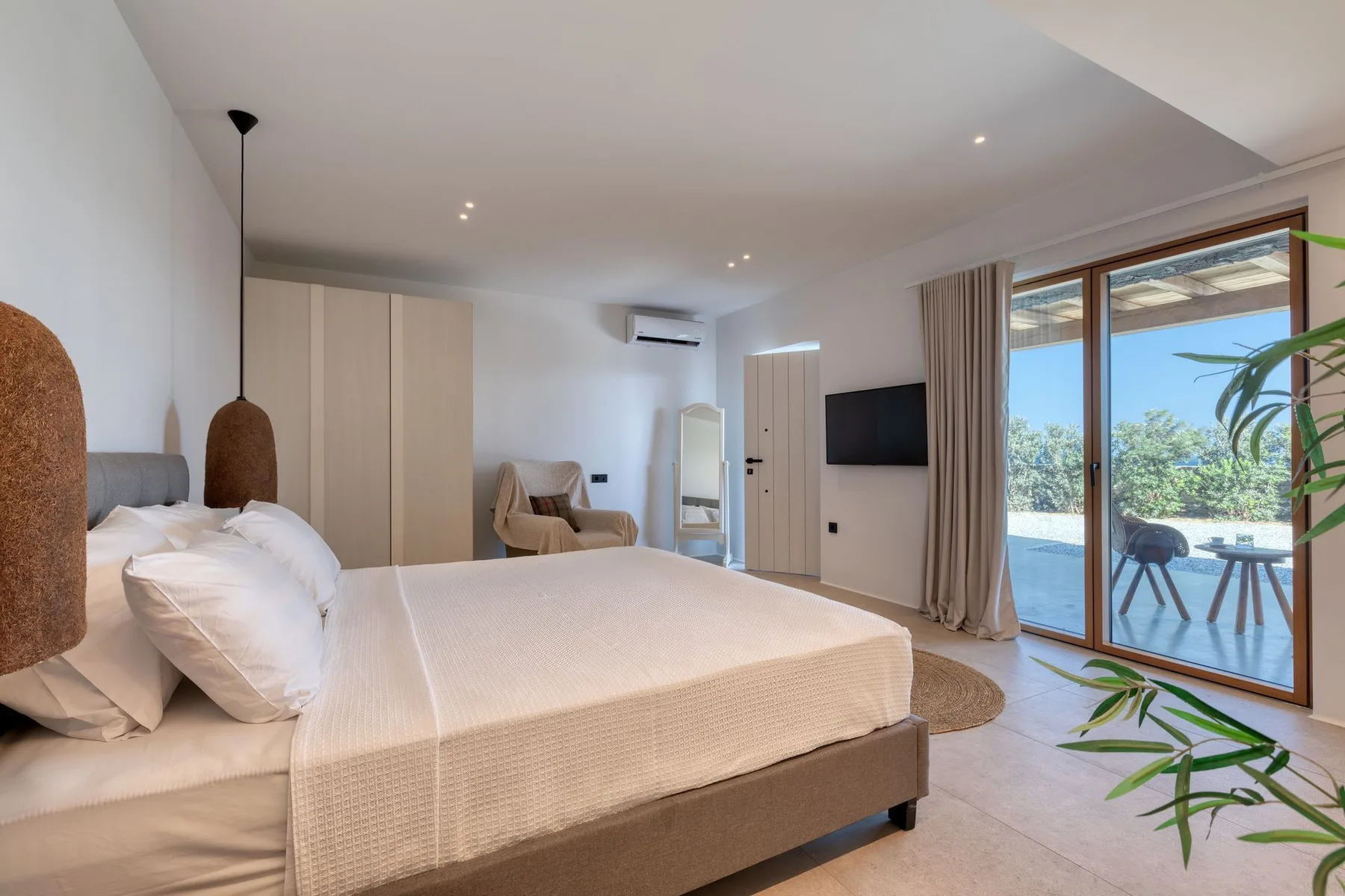 A bright bedroom with a large bed and sliding glass doors opening onto a patio.