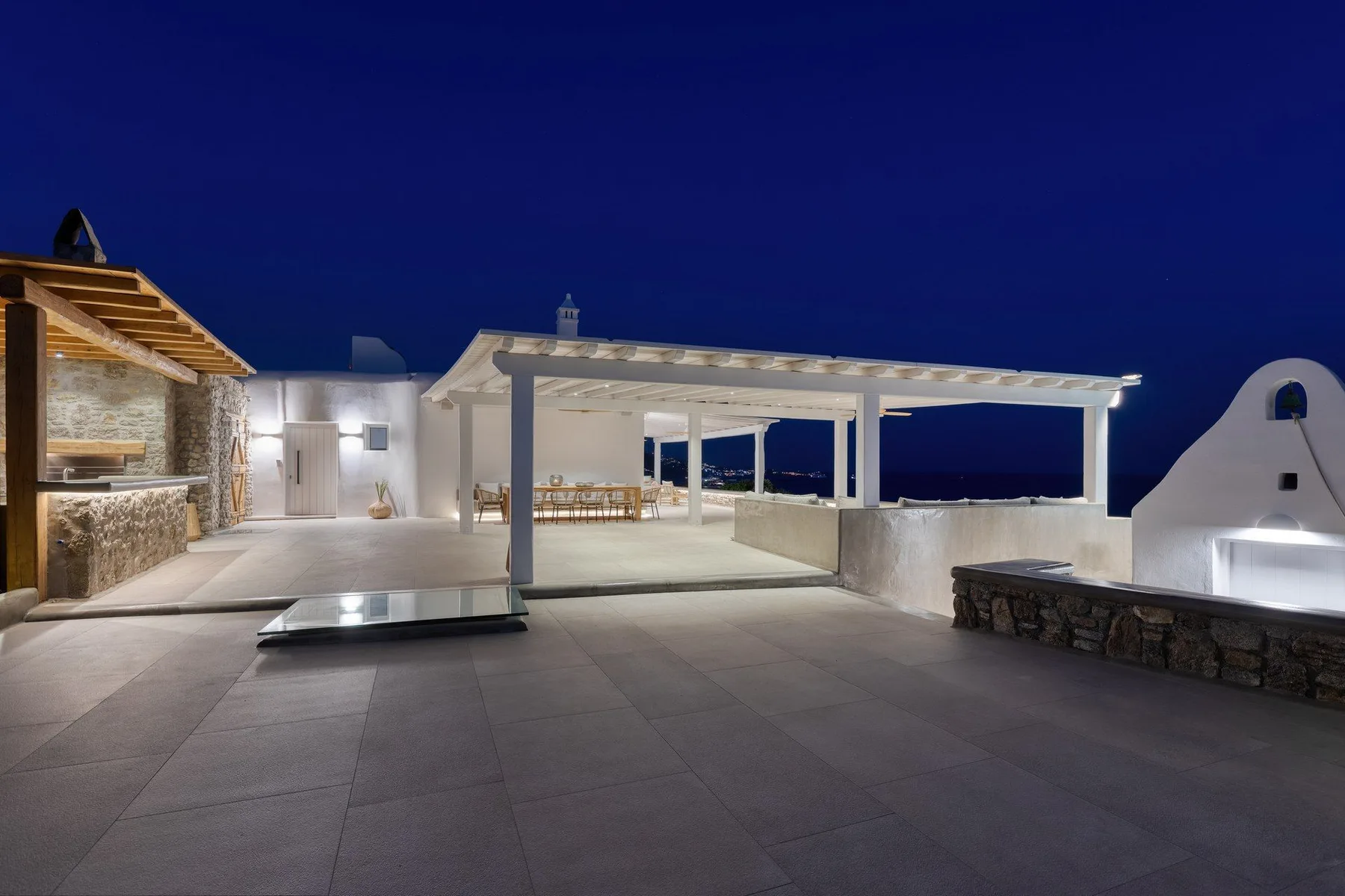 A spacious outdoor terrace at night with a covered seating area.