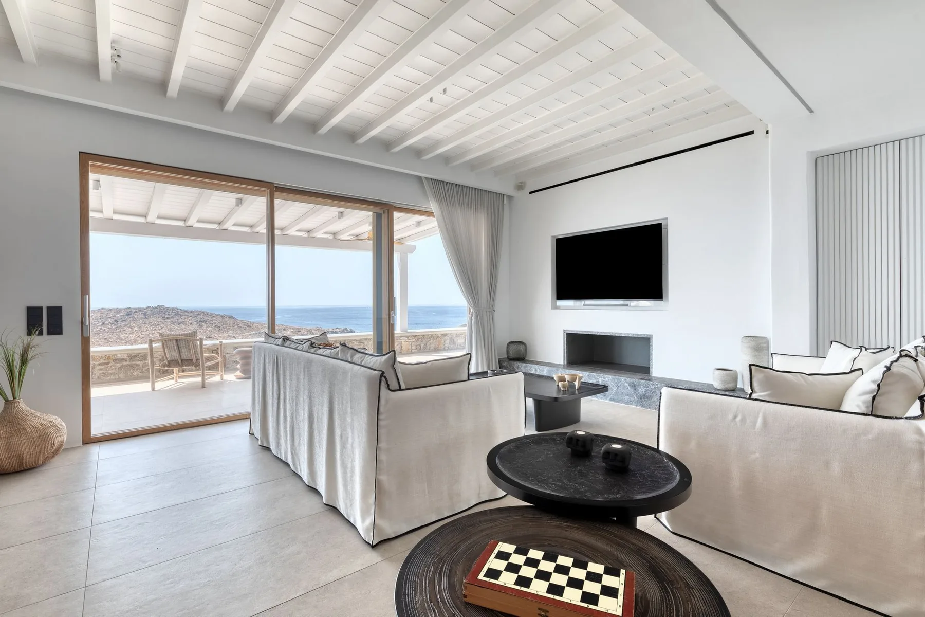 A bright living room opens onto a terrace through wide sliding glass doors.