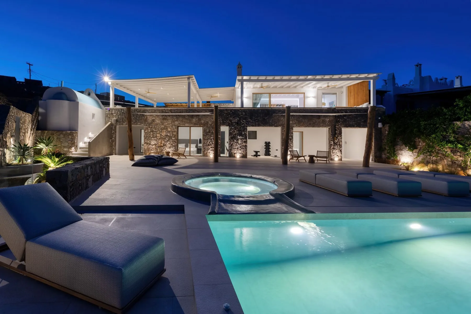 A rooftop pool and circular spa sit beside lounge seating at dusk.
