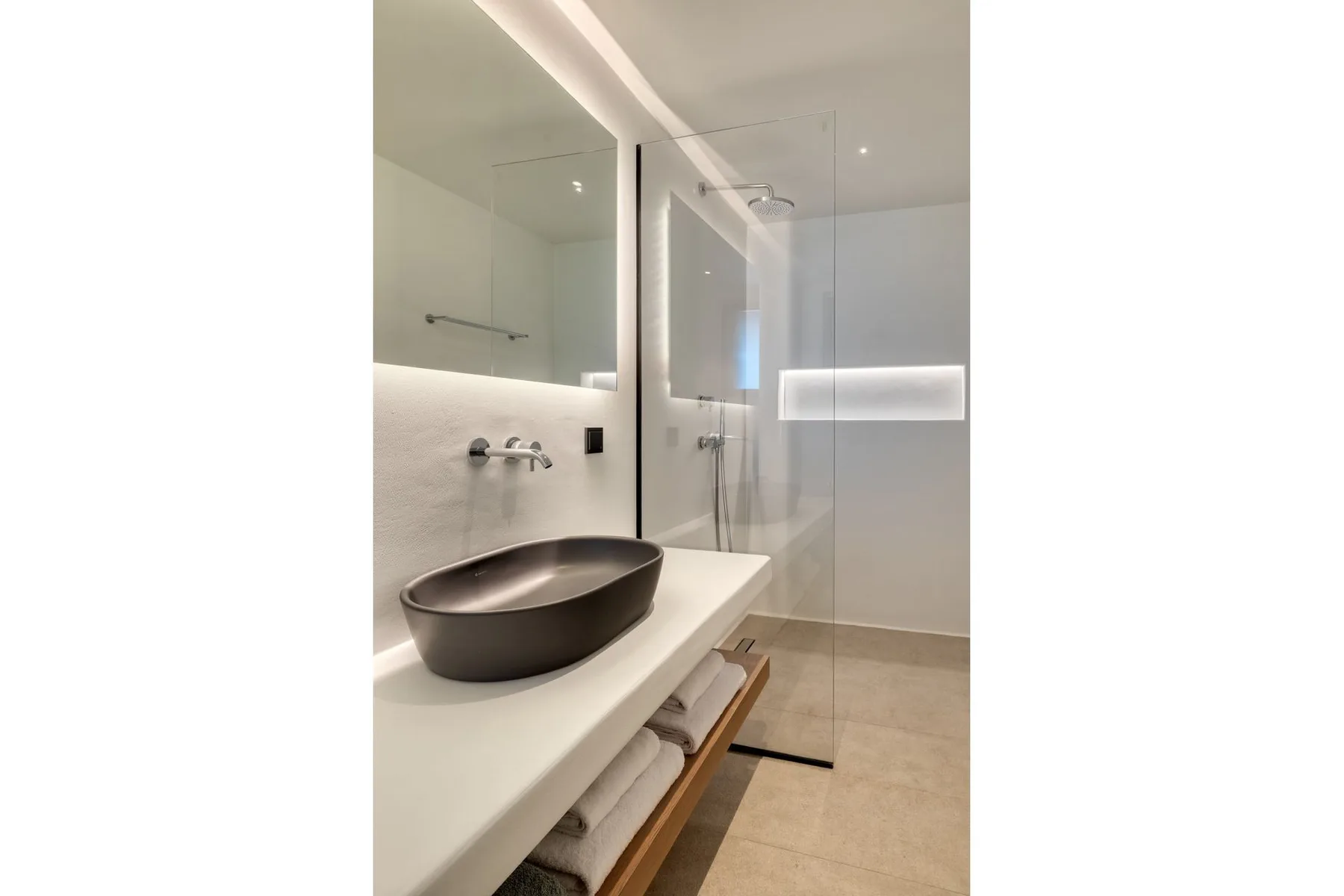 A modern bathroom with a vessel sink and glass shower.