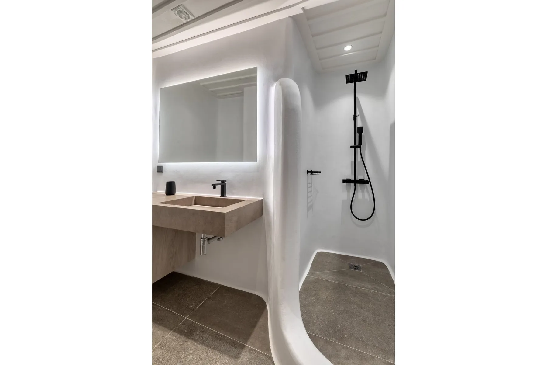 A modern bathroom with a wall-mounted sink and open shower.