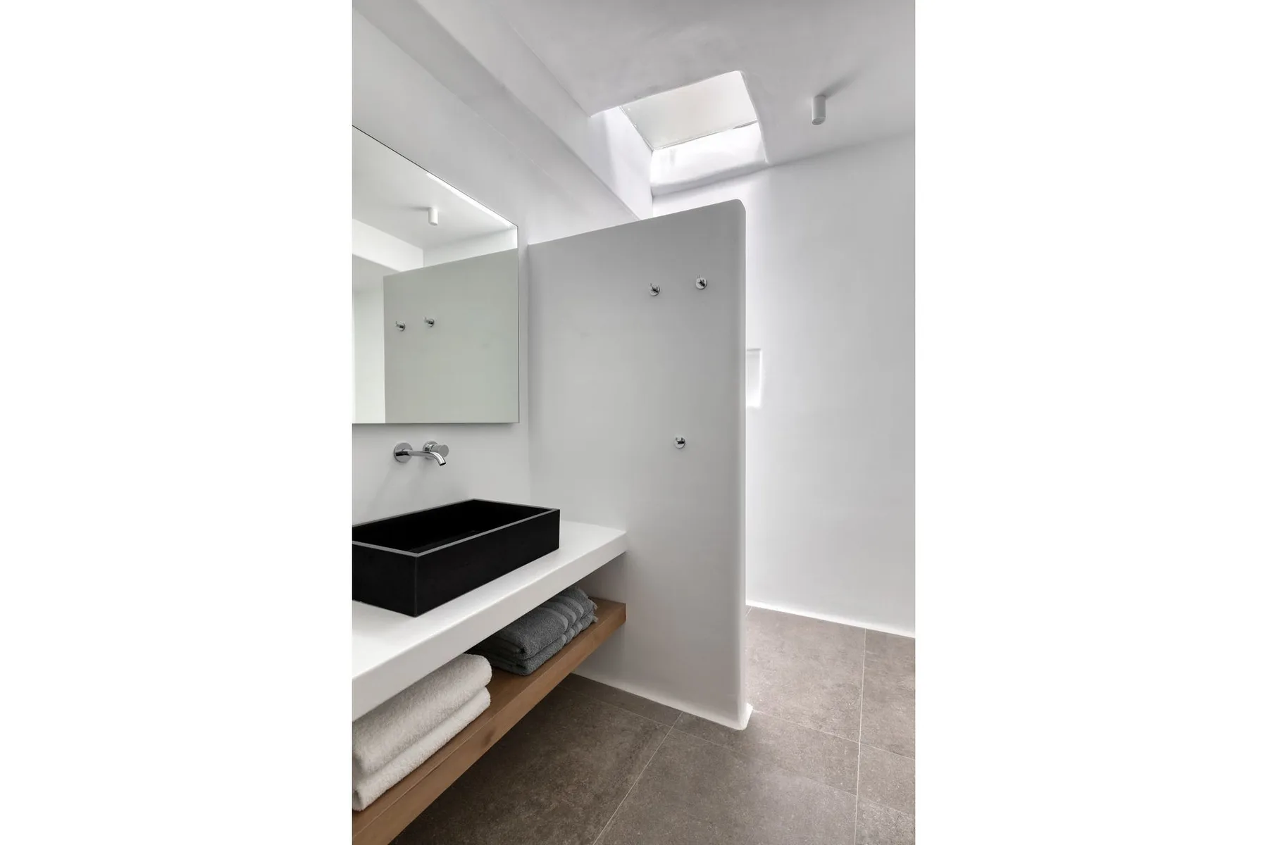 A bright bathroom with a black sink beneath a large wall mirror.