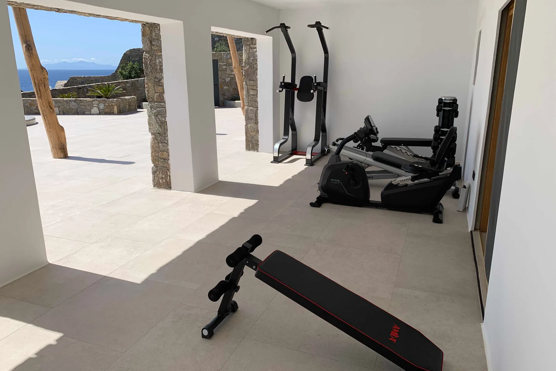 A gym with exercise equipment sits beside an open terrace.