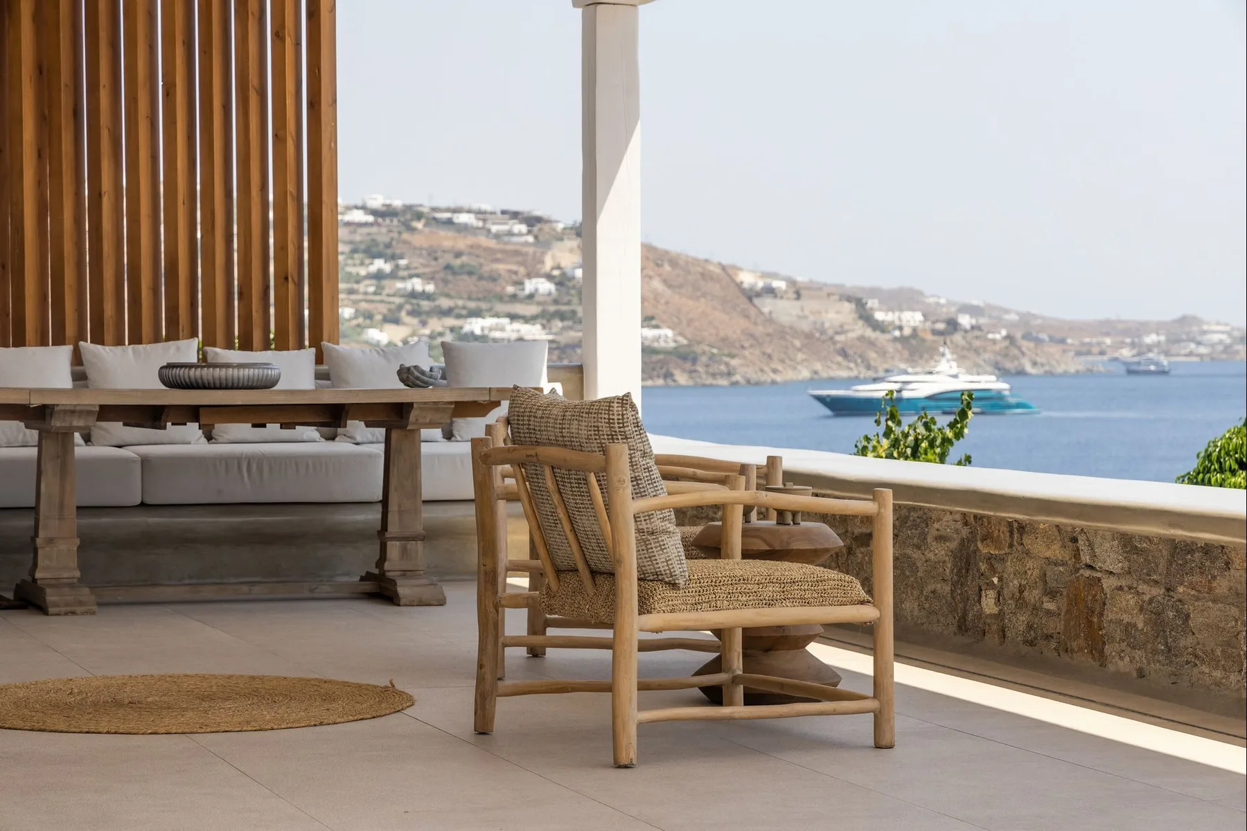 A seaside terrace with a dining table and seating overlooking the water.