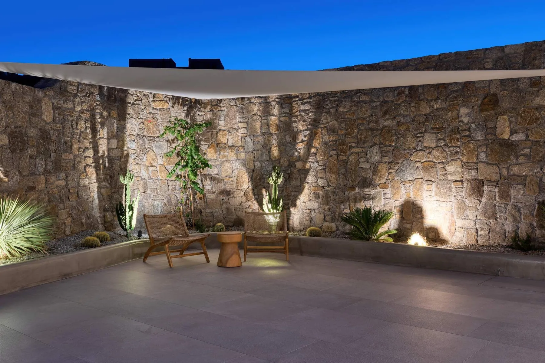 A stone-walled outdoor patio with seating and potted plants.