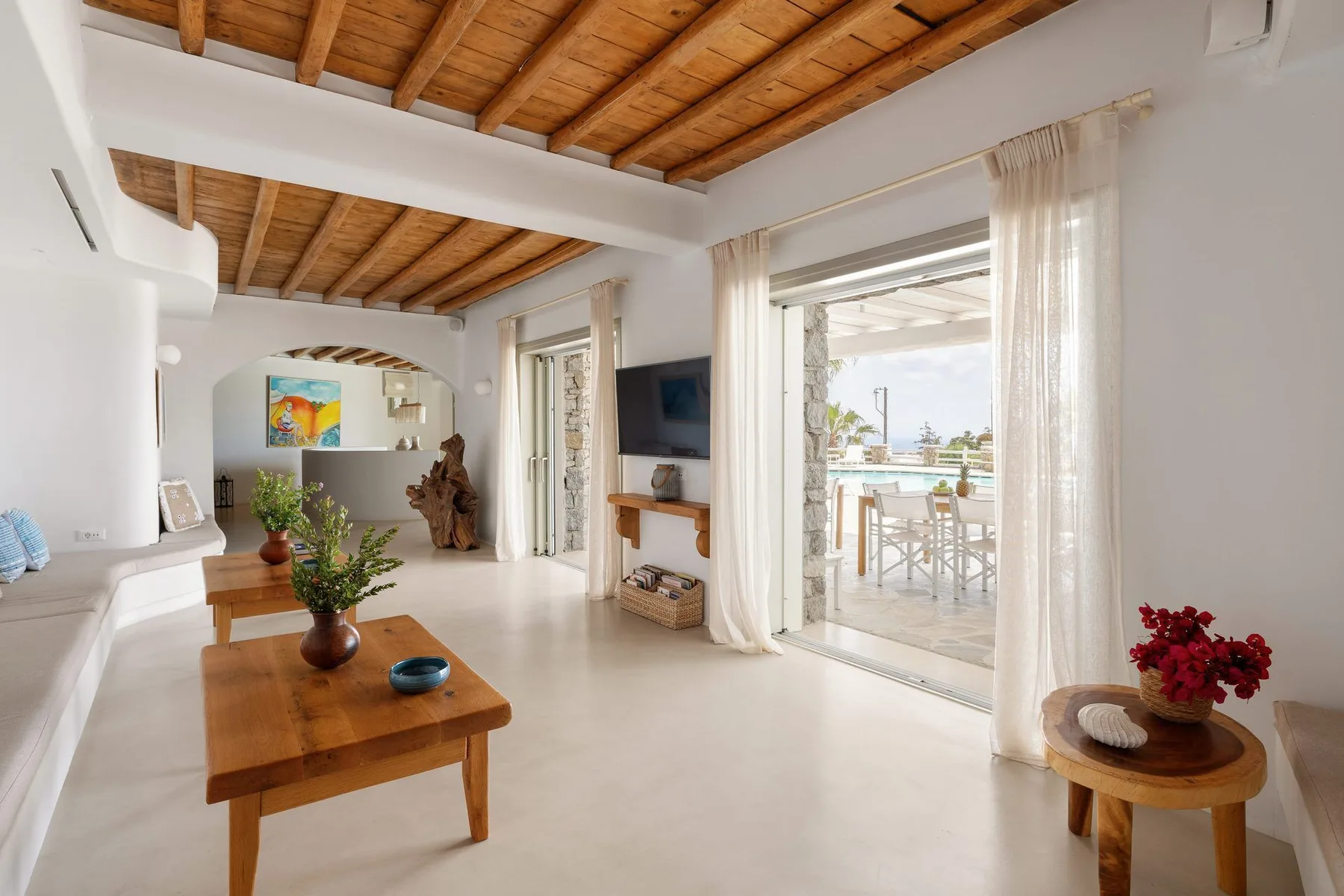 A bright living room opens onto a dining patio through wide glass doors.