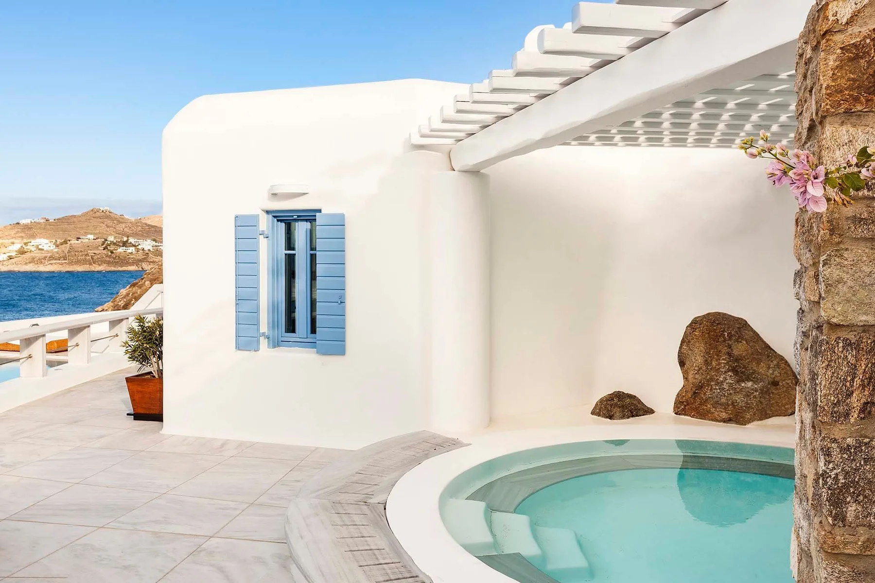 A white terrace beside a small pool overlooks the sea.