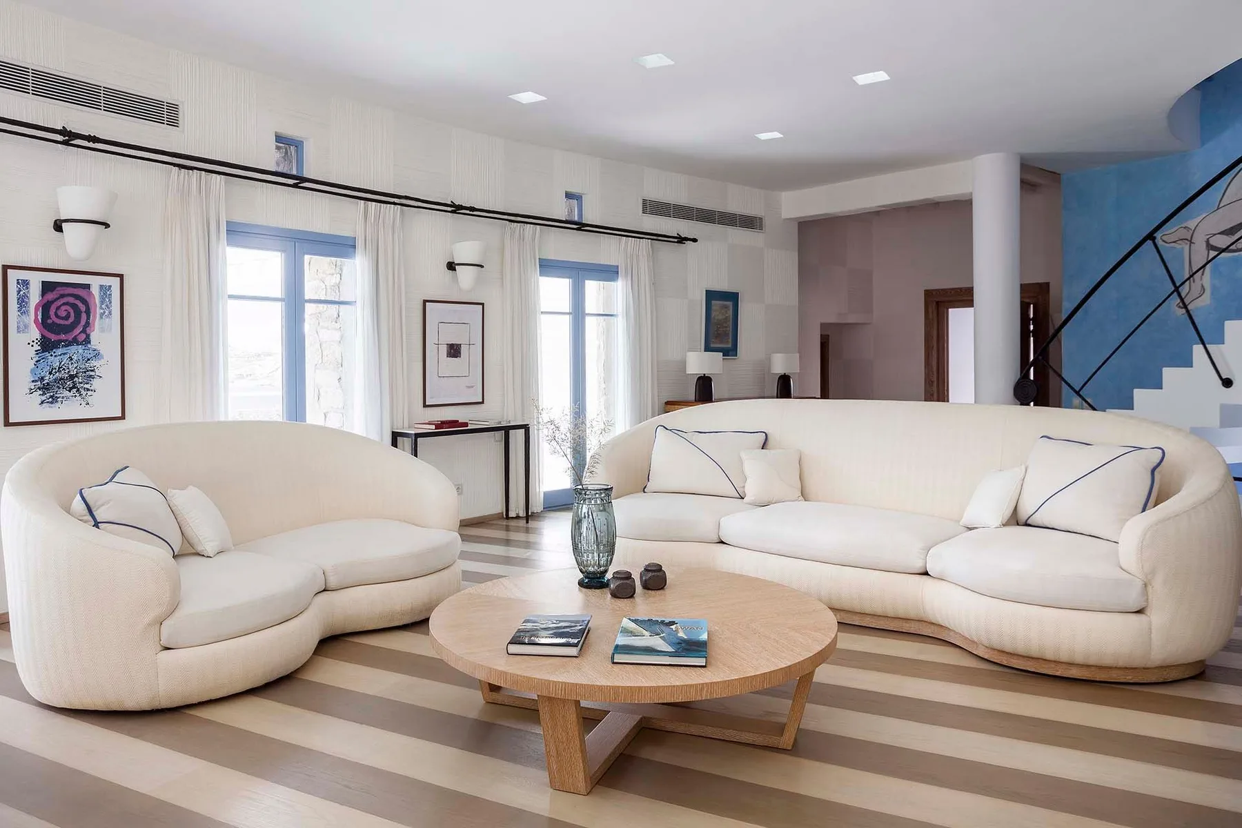 A bright living room with curved seating and a wooden coffee table.