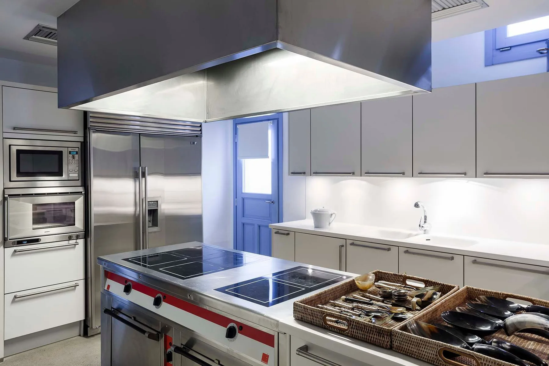 A modern kitchen with a large central cooktop and stainless steel appliances.