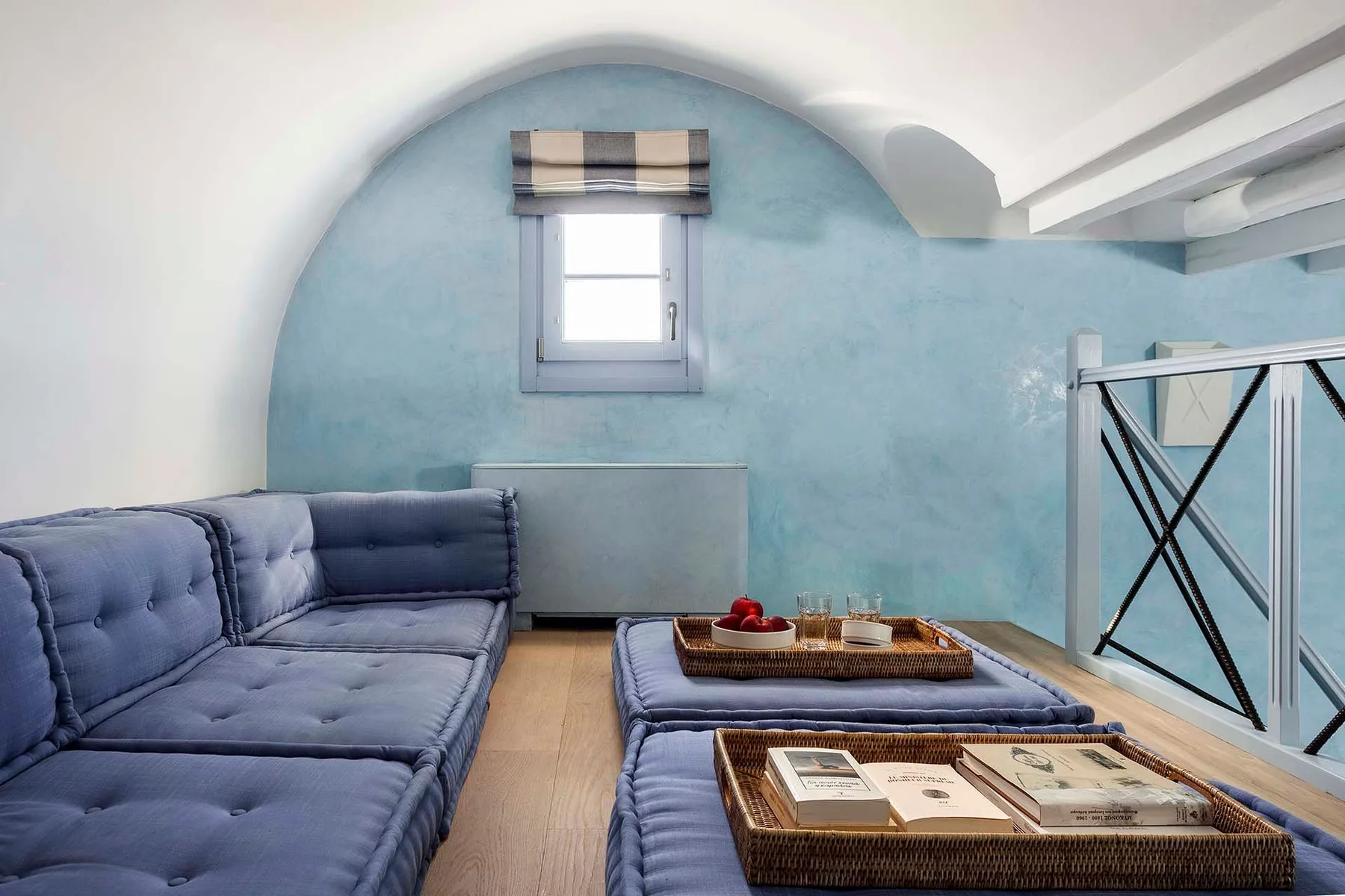 A sitting area with blue seating, a small window, and woven trays on low tables.