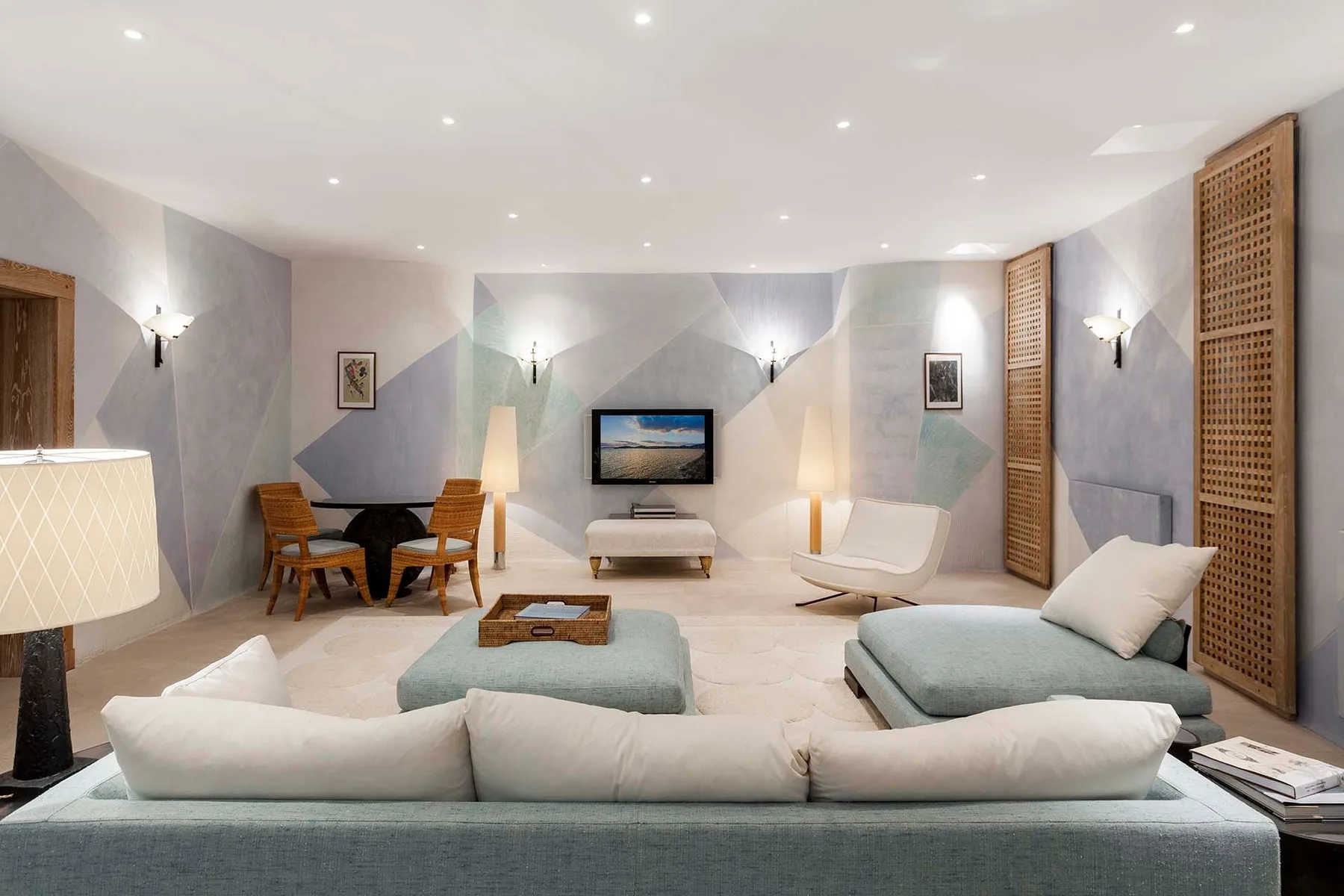 A contemporary living room with lounge seating, a television, and a small dining area.