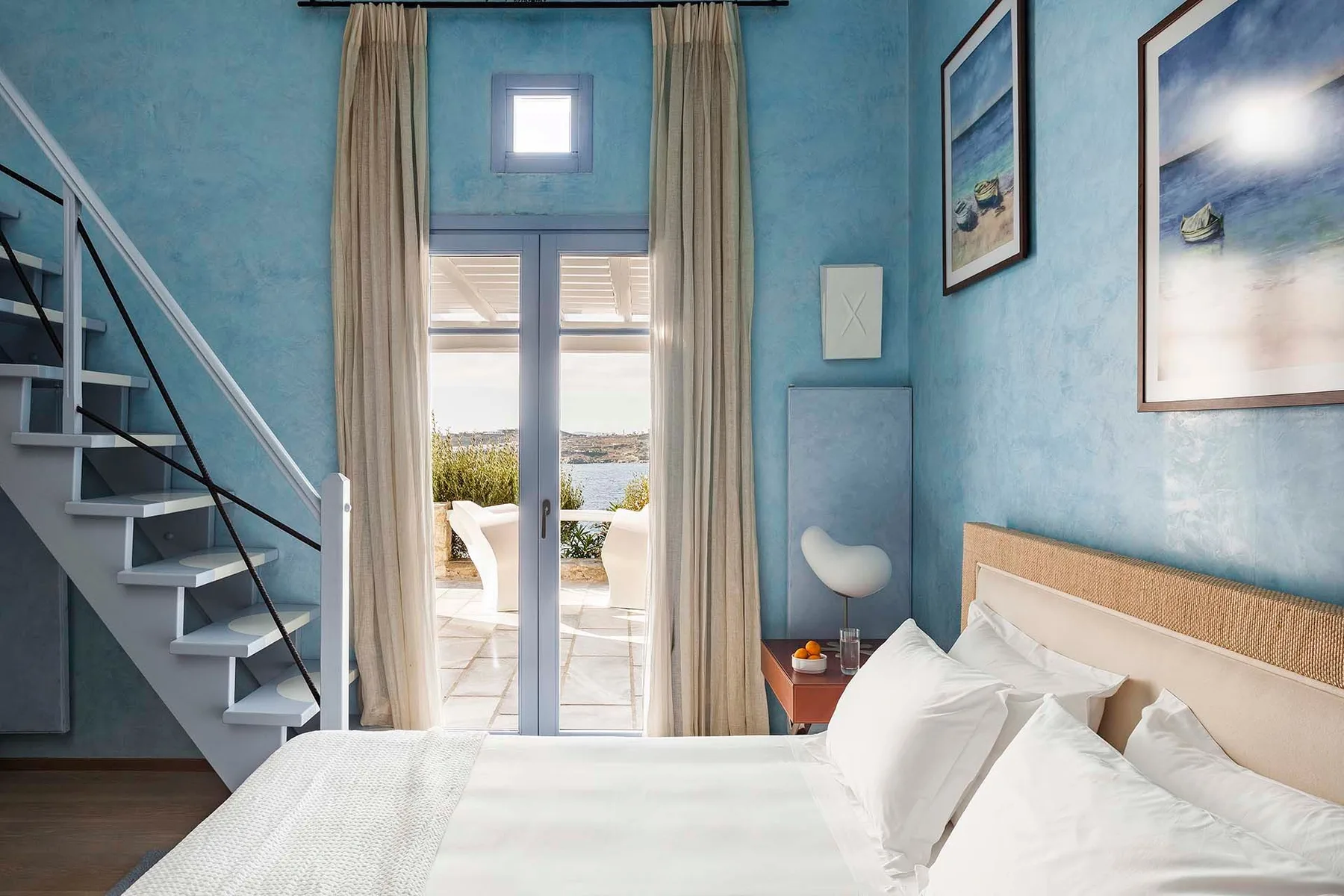 A bedroom with a bed, staircase, and glass doors opening onto a balcony.
