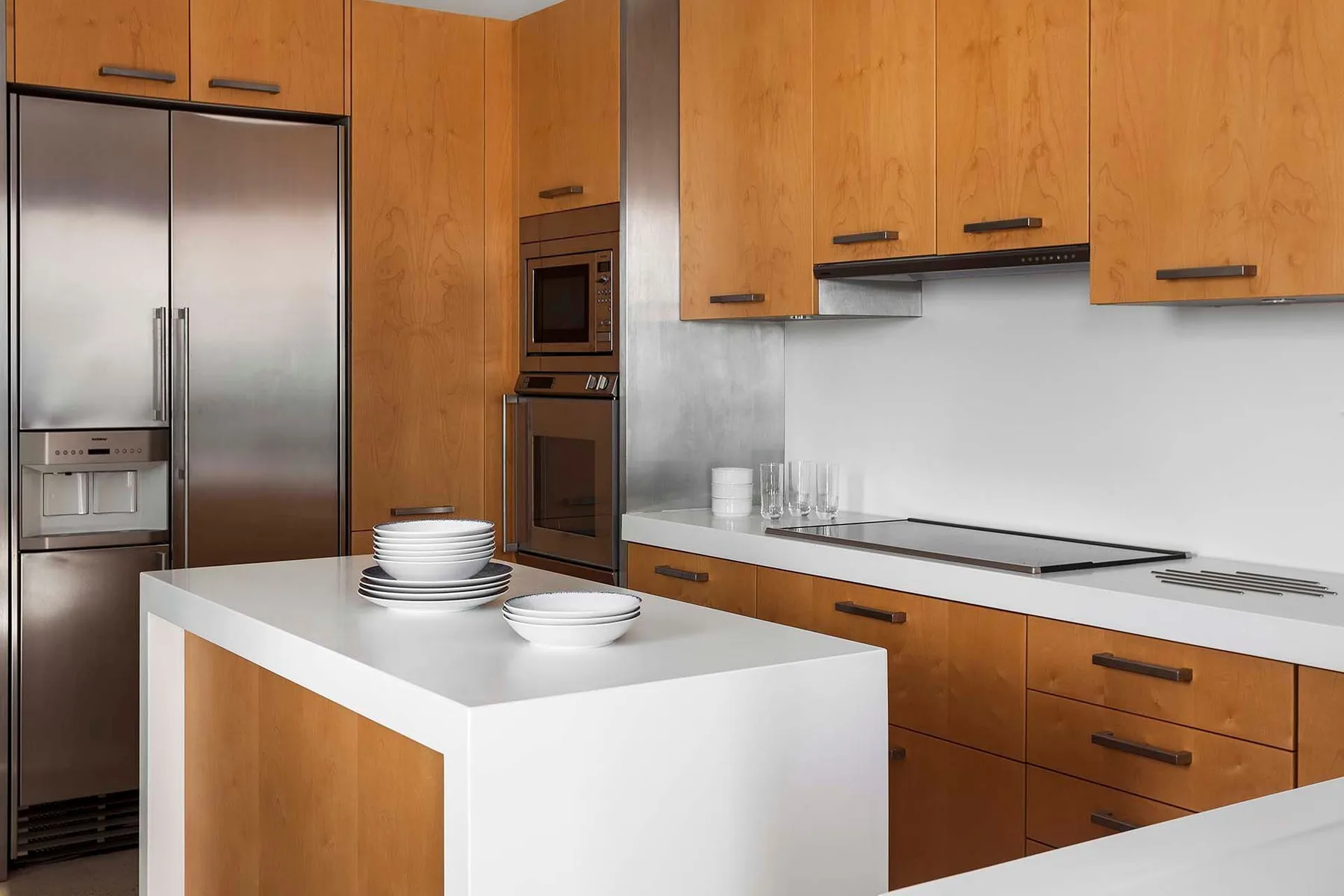 A modern kitchen with wood cabinetry, stainless steel appliances, and a white island.