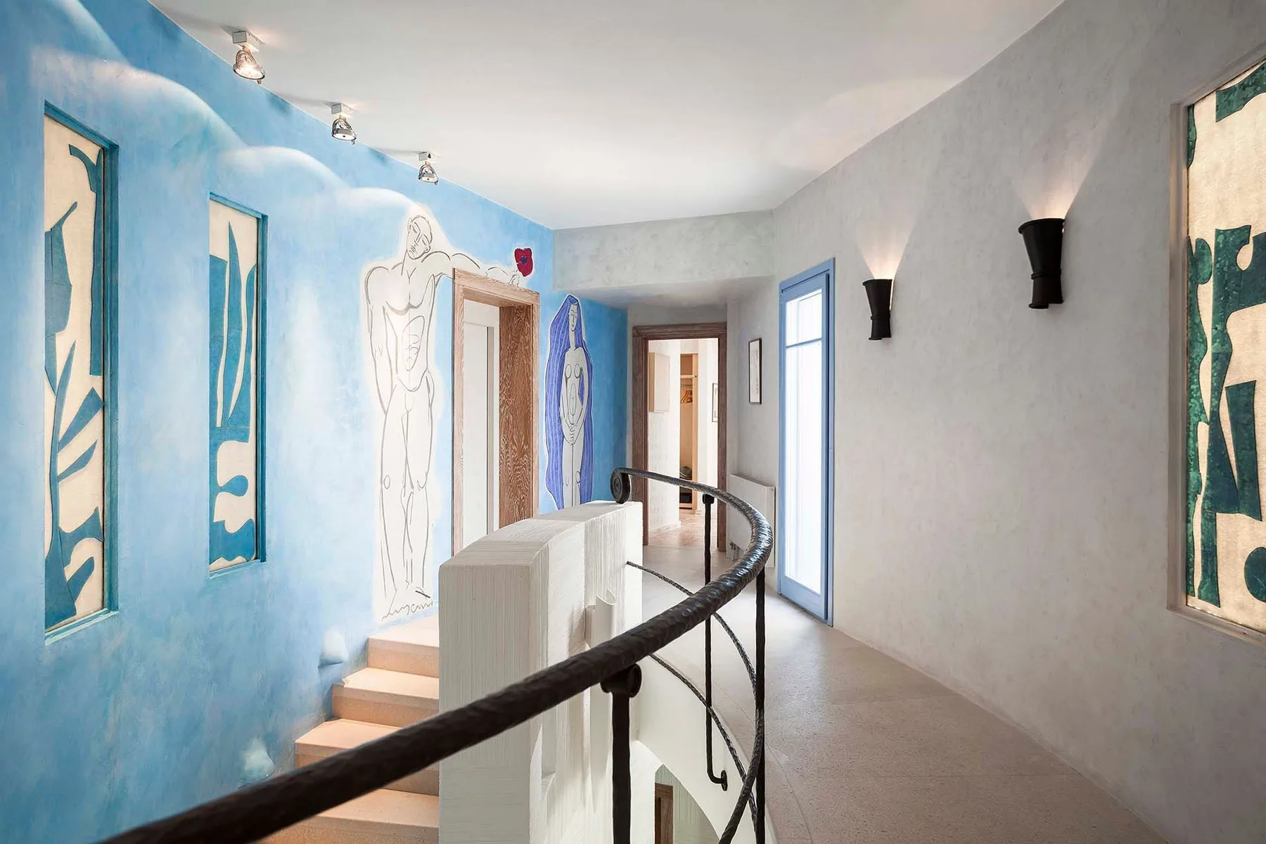A bright hallway with blue wall murals and a curved railing.