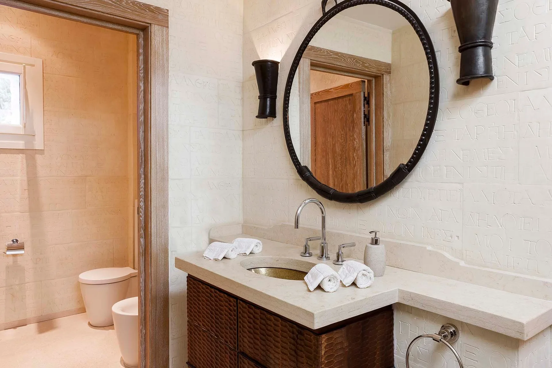 A bathroom vanity with a sink and oval mirror beside a tiled shower area.
