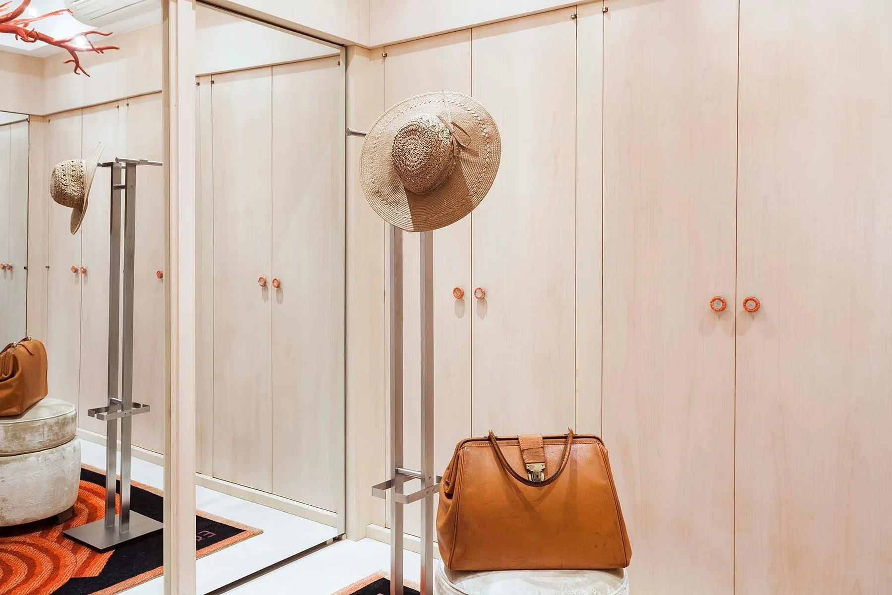 A dressing area with mirrored wardrobe doors and a brown handbag.