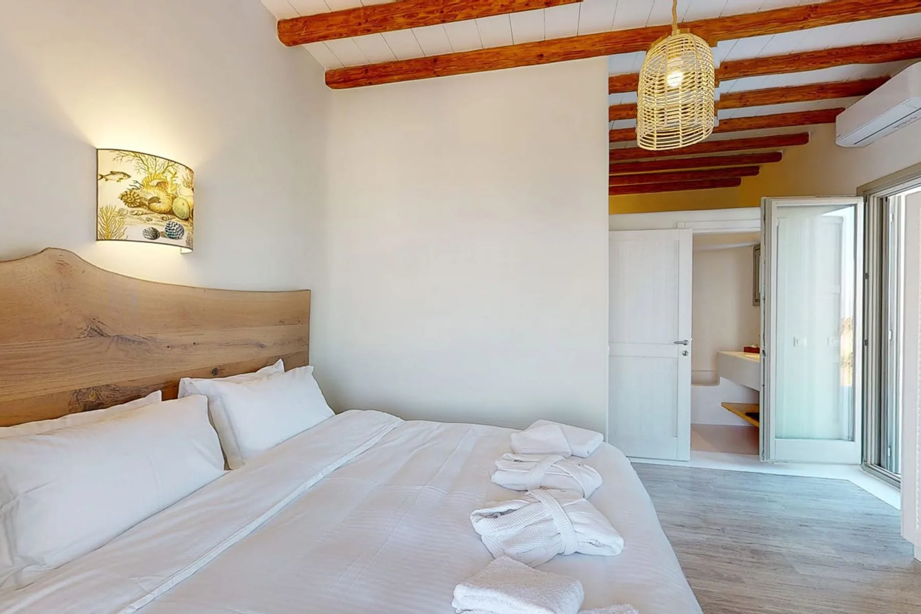 A bedroom with a bed, white linens, and exposed wooden ceiling beams.