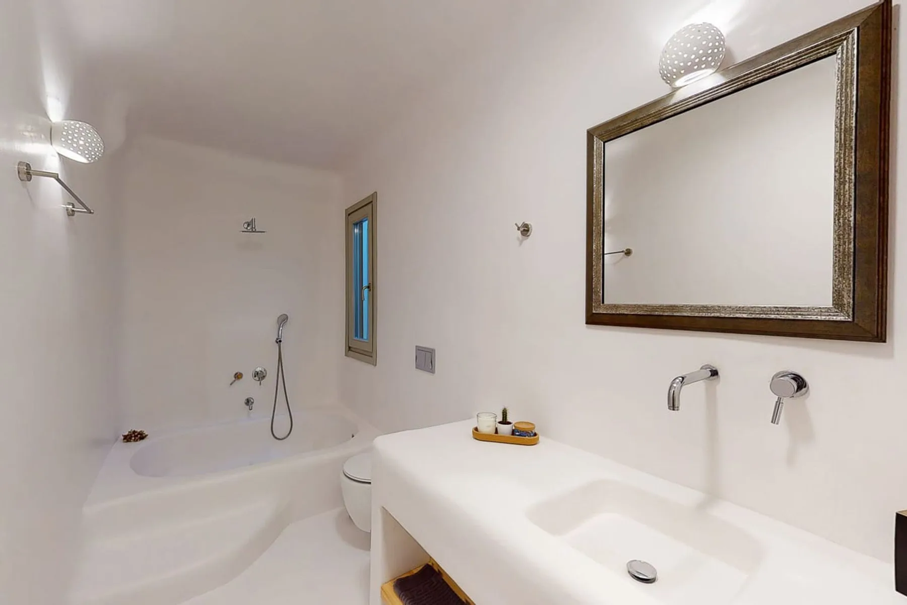 A bathroom with a bathtub and a large sink beneath a framed mirror.