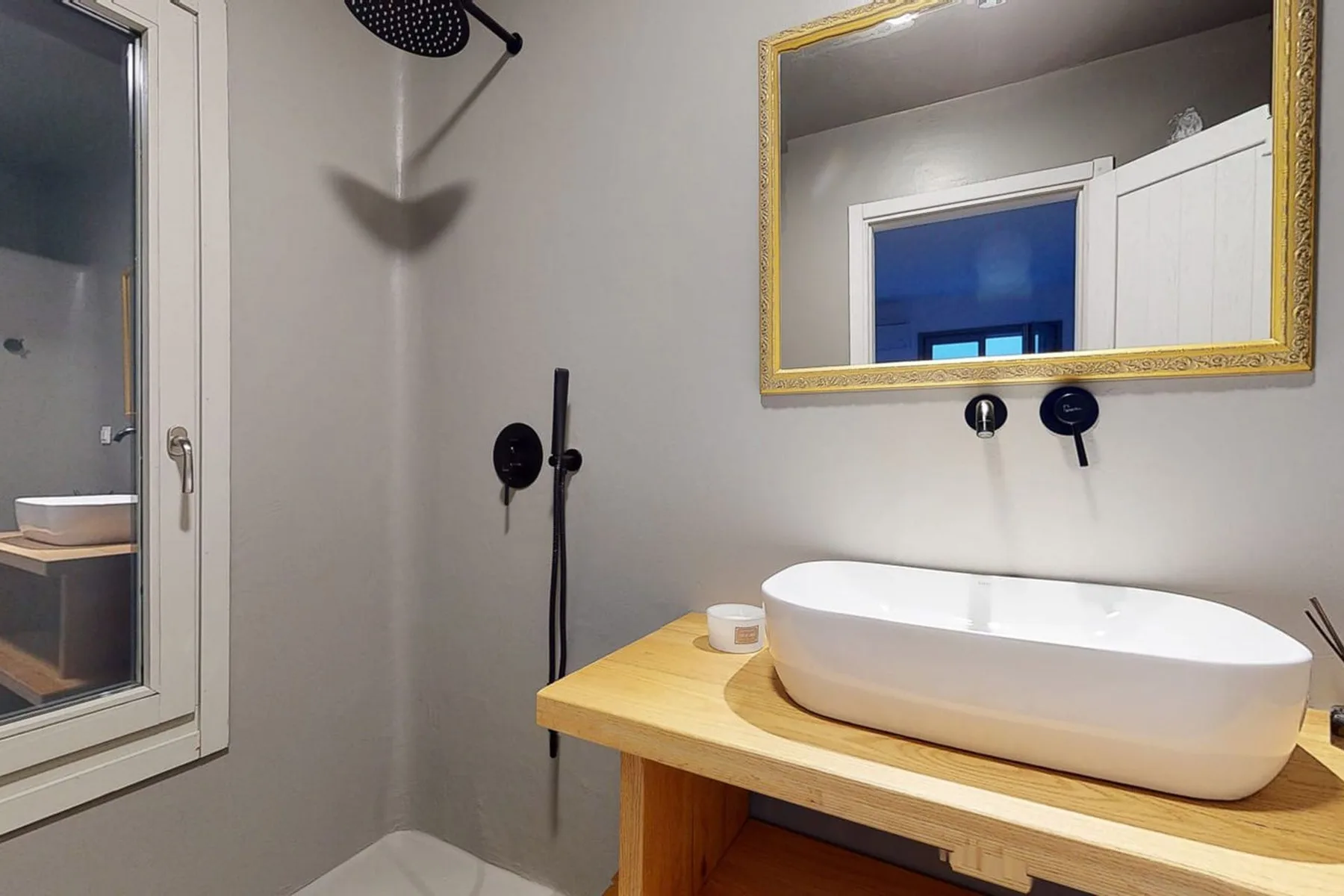 A modern bathroom with a white vessel sink on a wooden vanity.