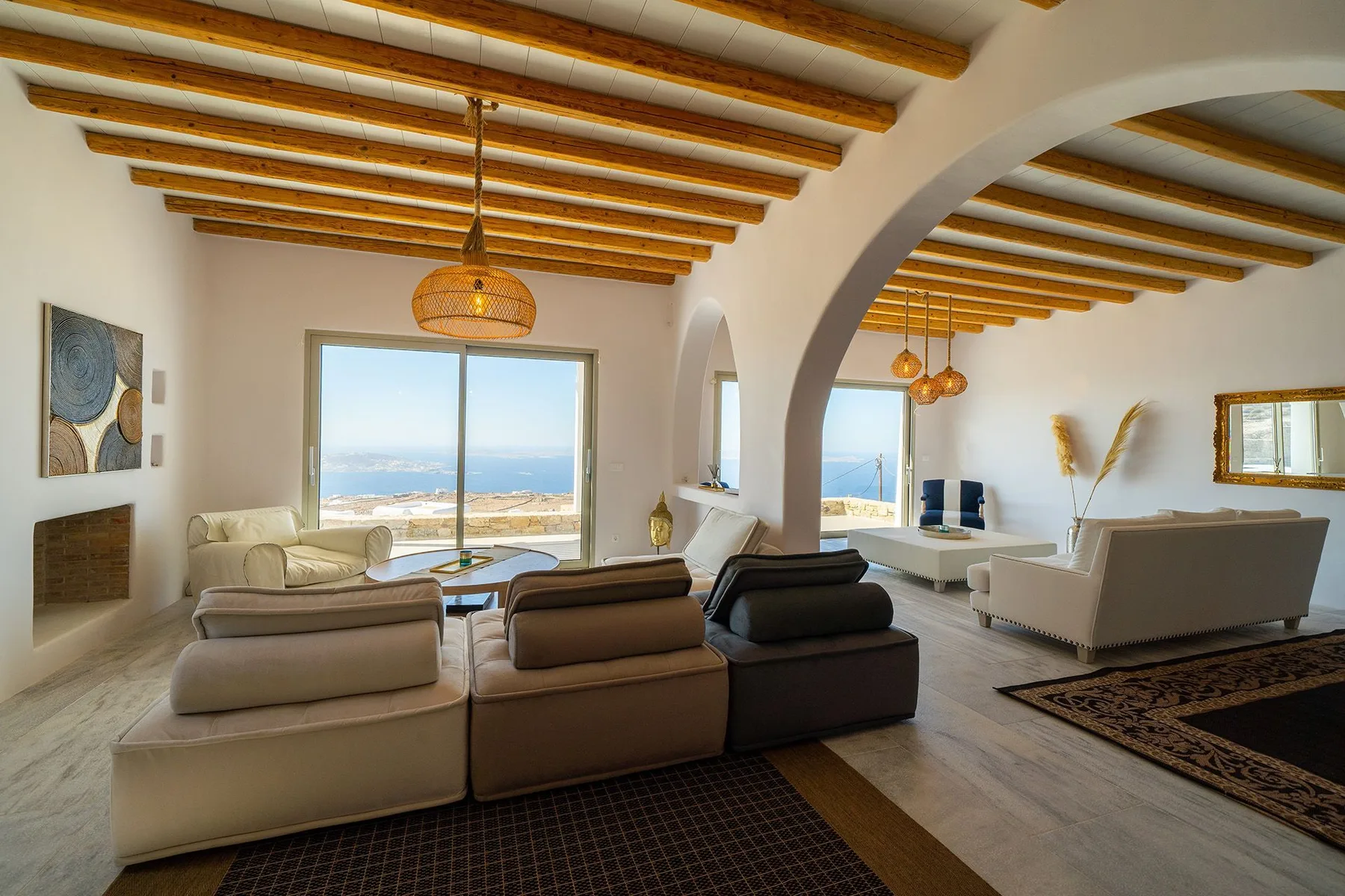 A bright living room with seating arranged around low tables and a wide ocean view.