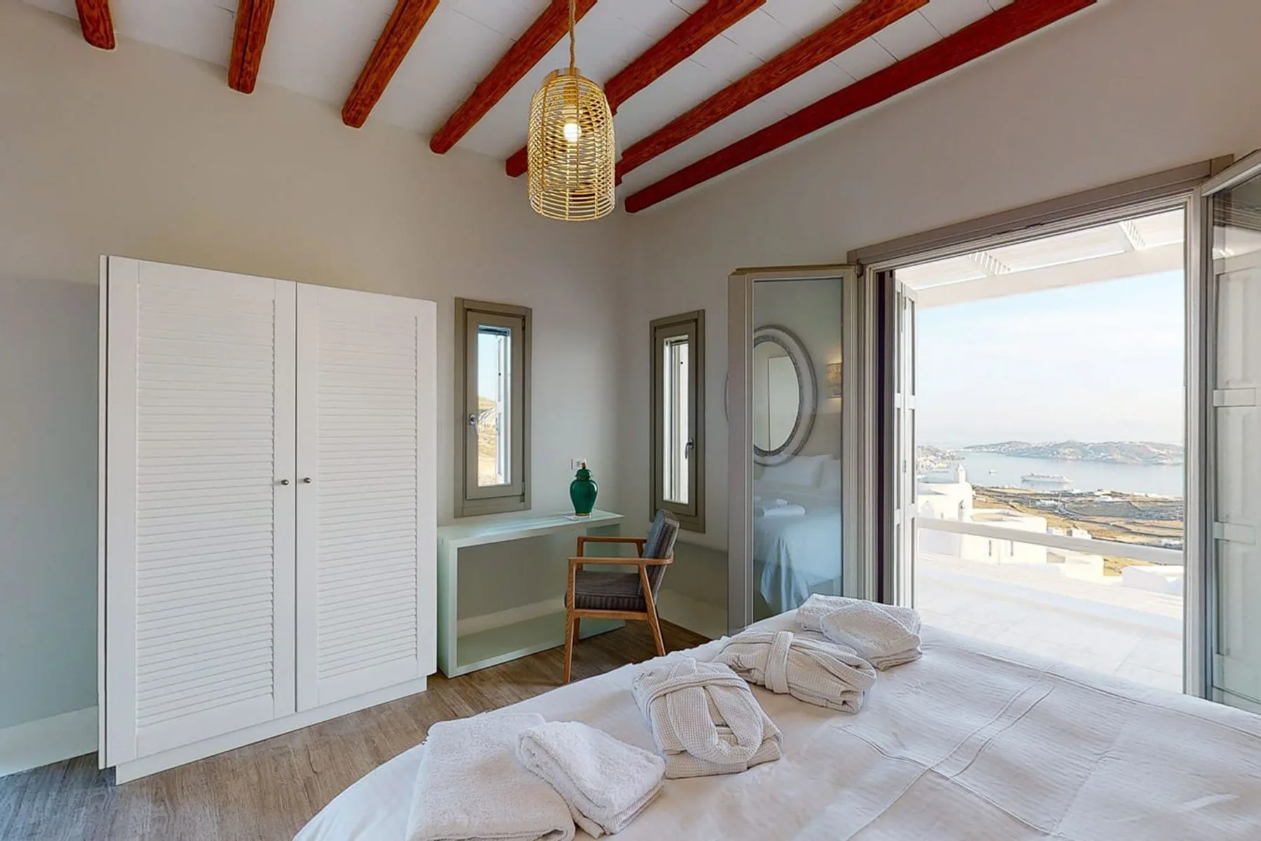 A bright bedroom opens onto a balcony with views of the sea.