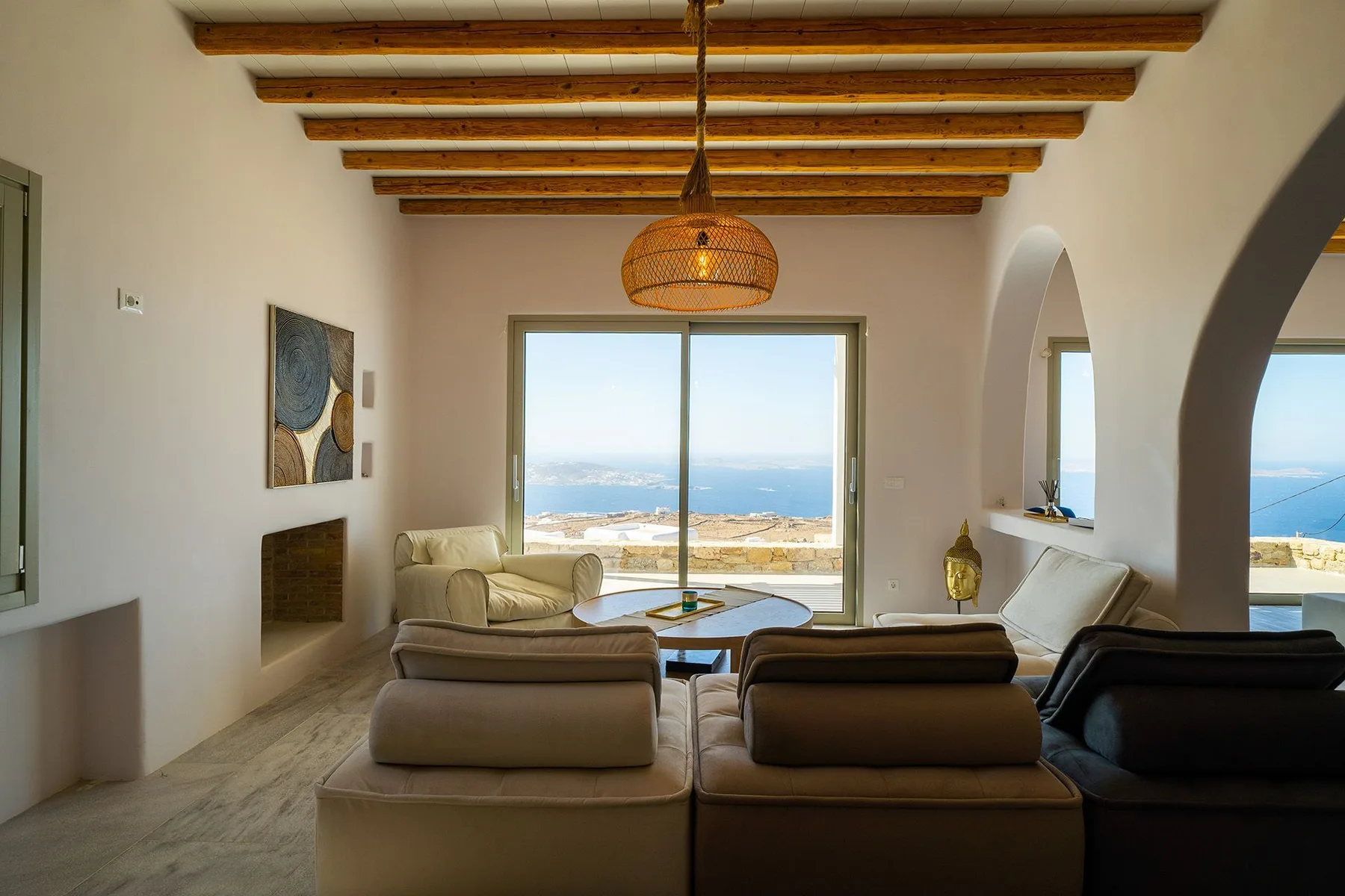 A living room with seating and large windows overlooking the sea.
