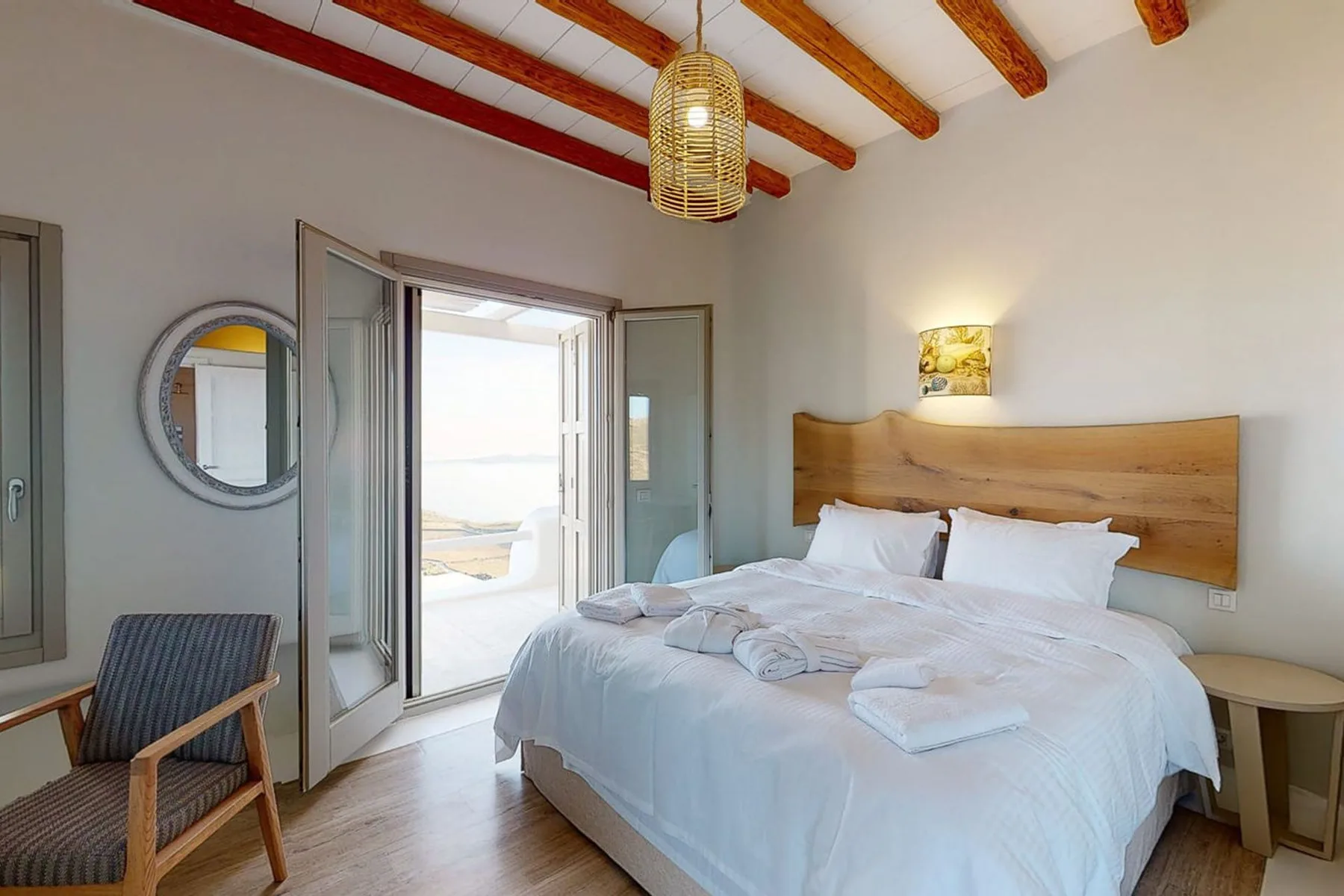 A bright bedroom with a large bed and open doors leading to a balcony.