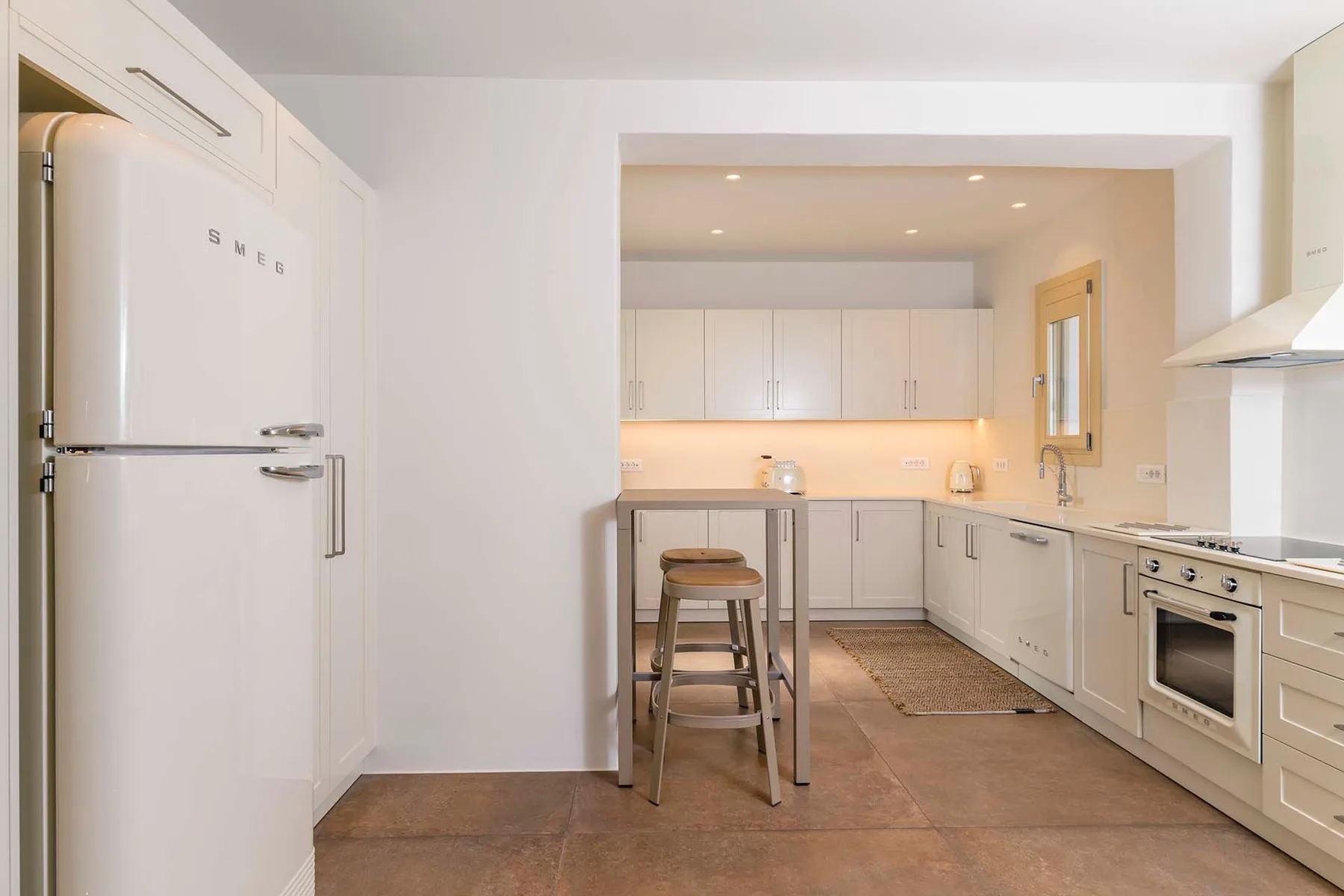 A bright kitchen with white cabinetry, a refrigerator, and a central island.