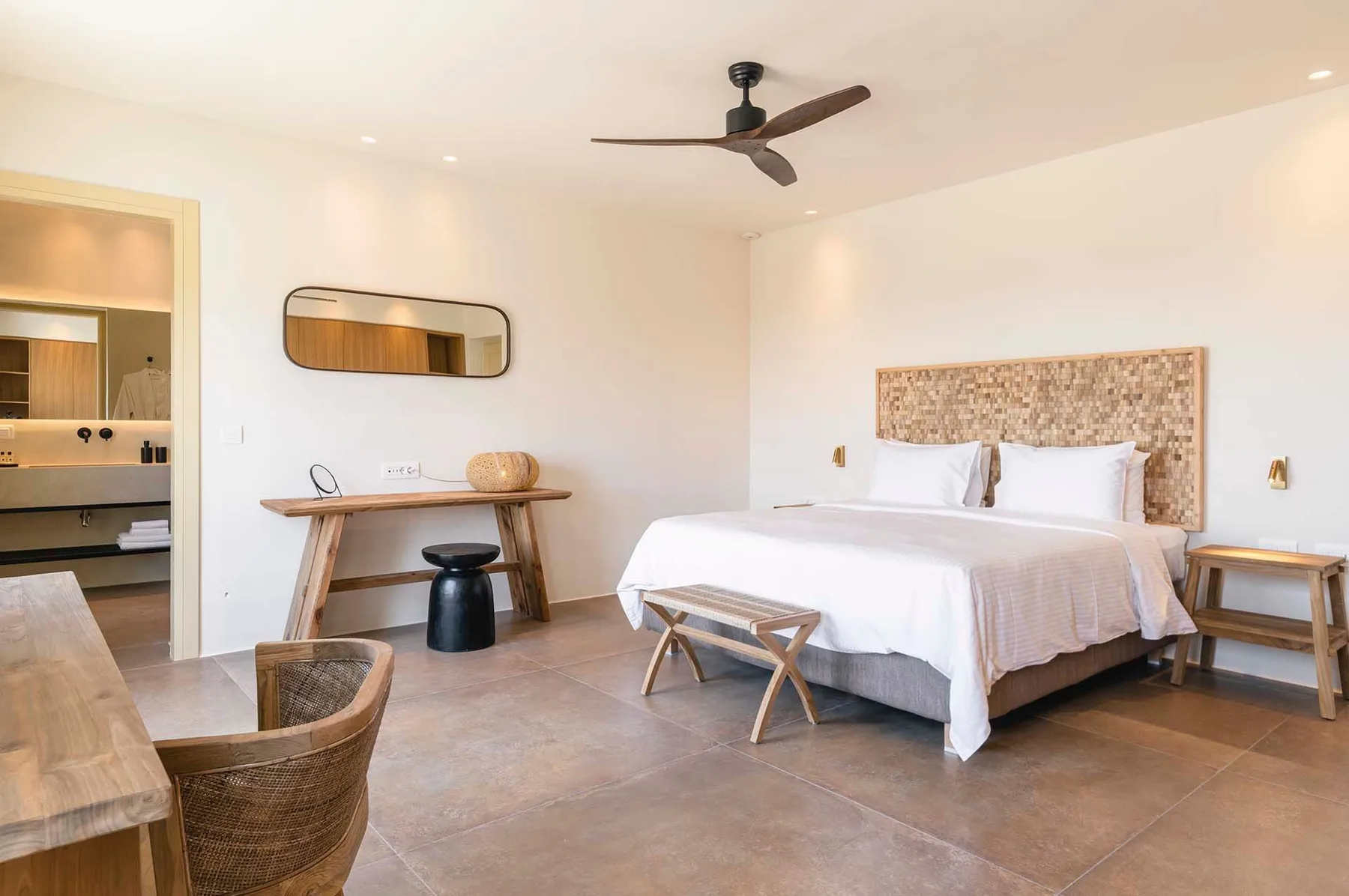 A bright bedroom with a bed, a wooden headboard, and a ceiling fan.