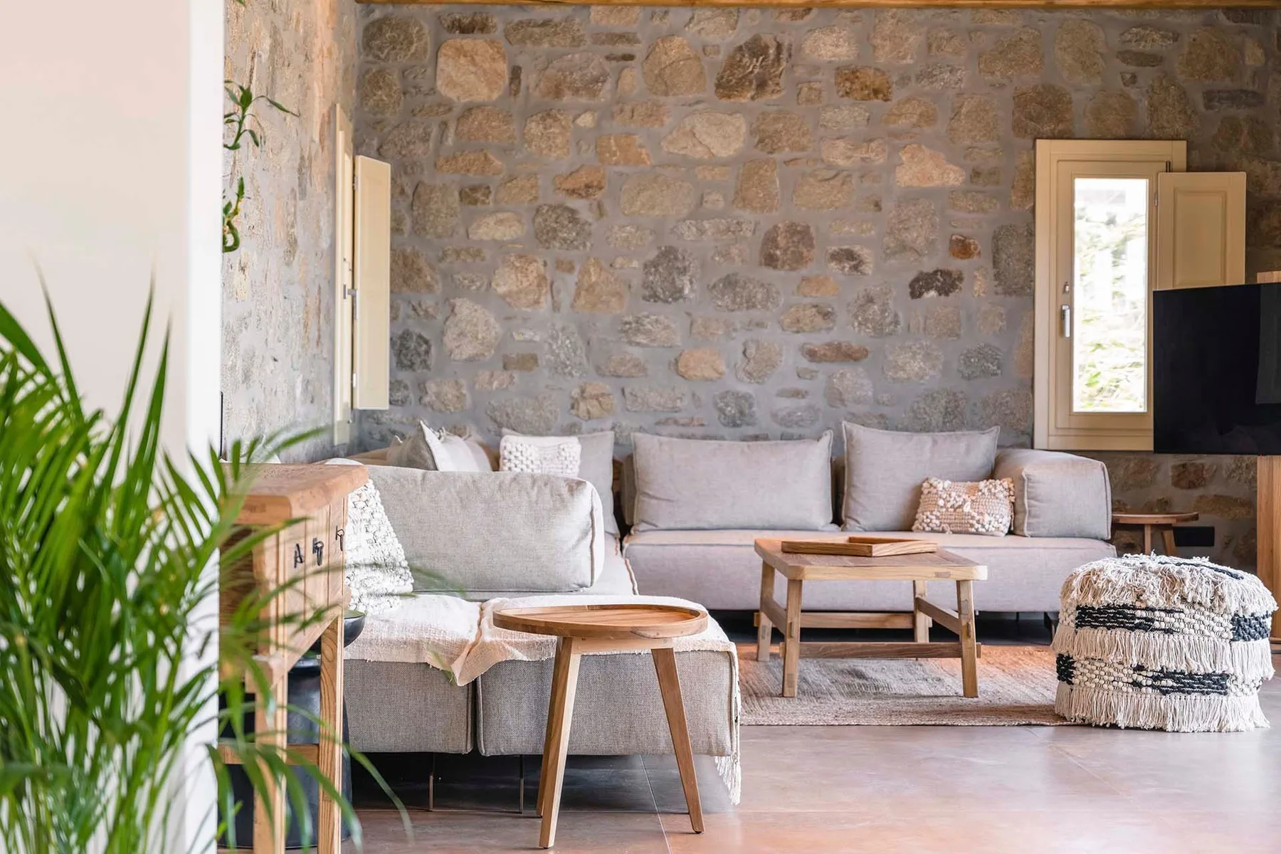 A living room with light seating and a stone wall.
