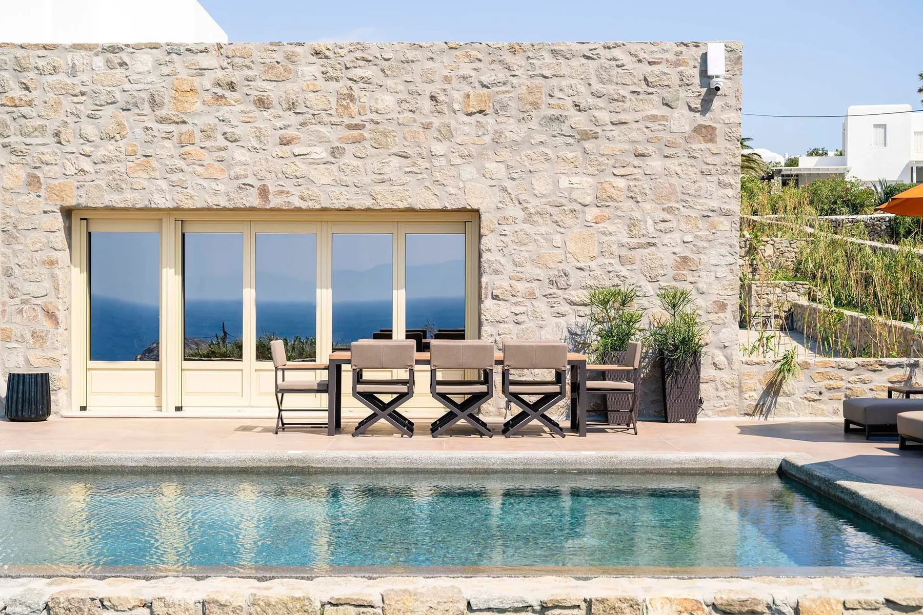 A poolside patio with outdoor seating in front of a stone wall.