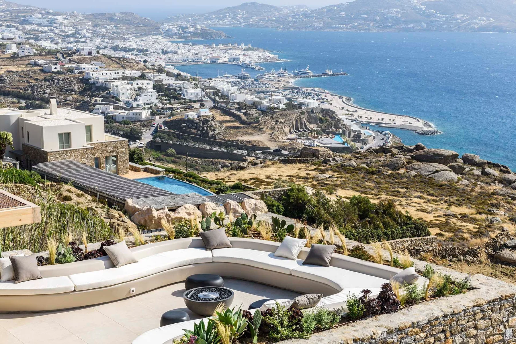 A curved outdoor seating area overlooks a coastal town and the sea.