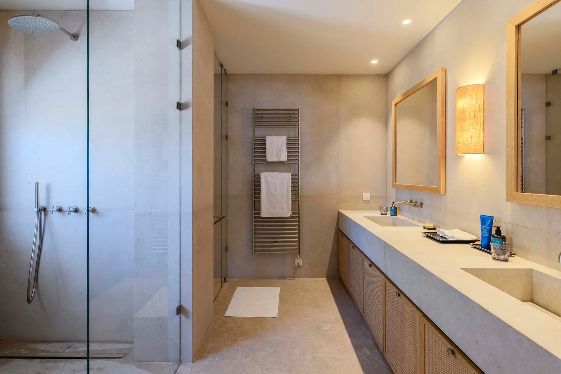 A modern bathroom with a glass shower and a long vanity.